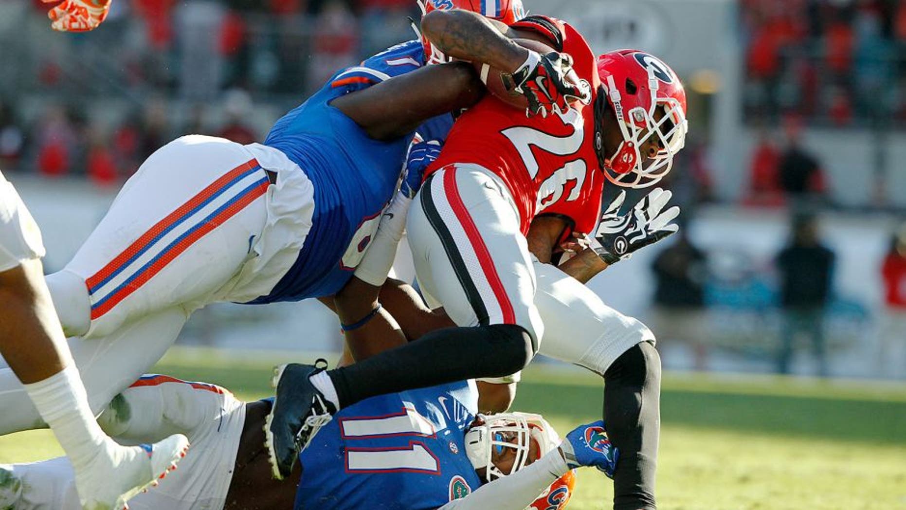 Nov 1, 2014; Jacksonville, FL, USA; Georgia Bulldogs wide receiver Malcolm Mitchell (26) is tackled by Florida Gators defensive lineman Leon Orr (8) and linebacker Neiron Ball (11) during the first half at EverBank Field. Mandatory Credit: Kim Klement-USA TODAY Sports