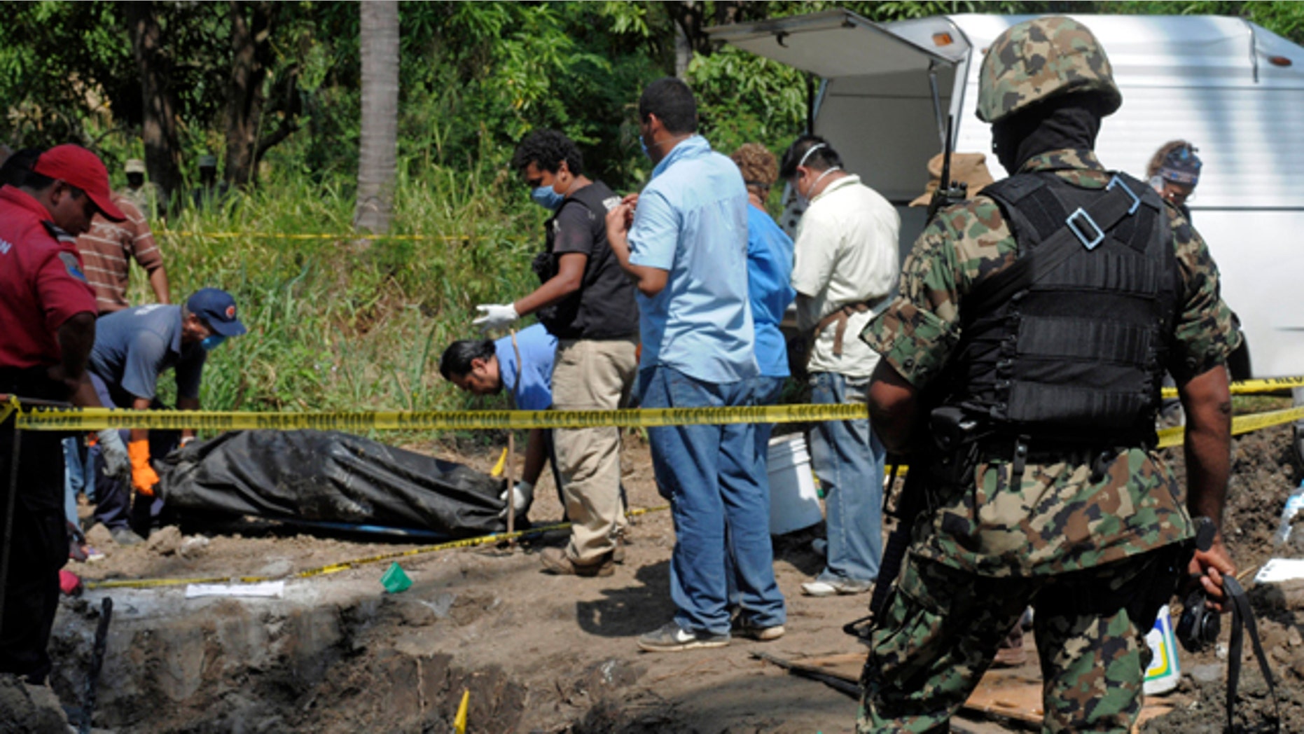 Nov. 3: A Mexican Navy soldier watch as forensic workers remove a body which was buried at a field in the town of Tuncingo, southern Mexico.