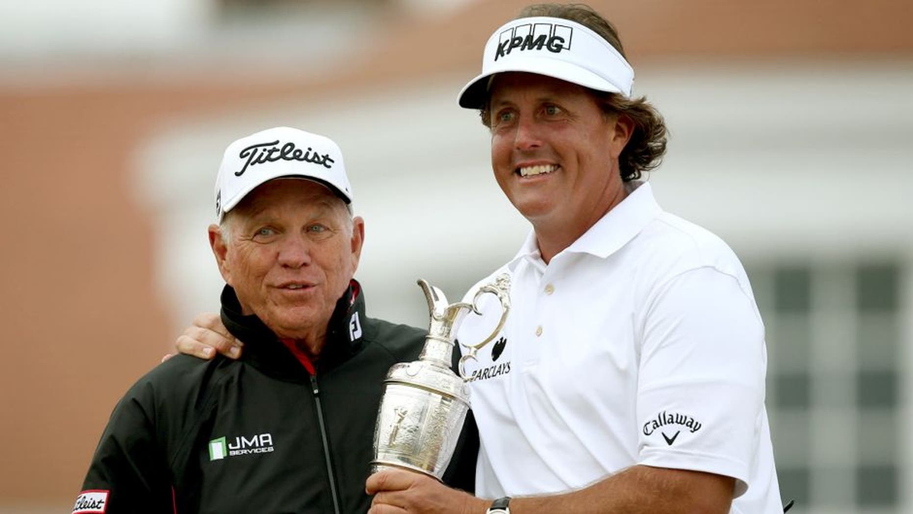 US golfer Phil Mickelson poses for pictures with his coach Butch Harmon and his trophy the Claret Jug after winning the 2013 British Open Golf Championship at Muirfield golf course at Gullane in Scotland on July 21, 2013. Mickelson won the British Open at Muirfield with a superb final round of 66. The 43-year-old American won with a three under total of 281, three strokes clear of Henrik Stenson who had a closing 70.AFP PHOTO/ADRIAN DENNIS (Photo credit should read ADRIAN DENNIS/AFP/Getty Images)