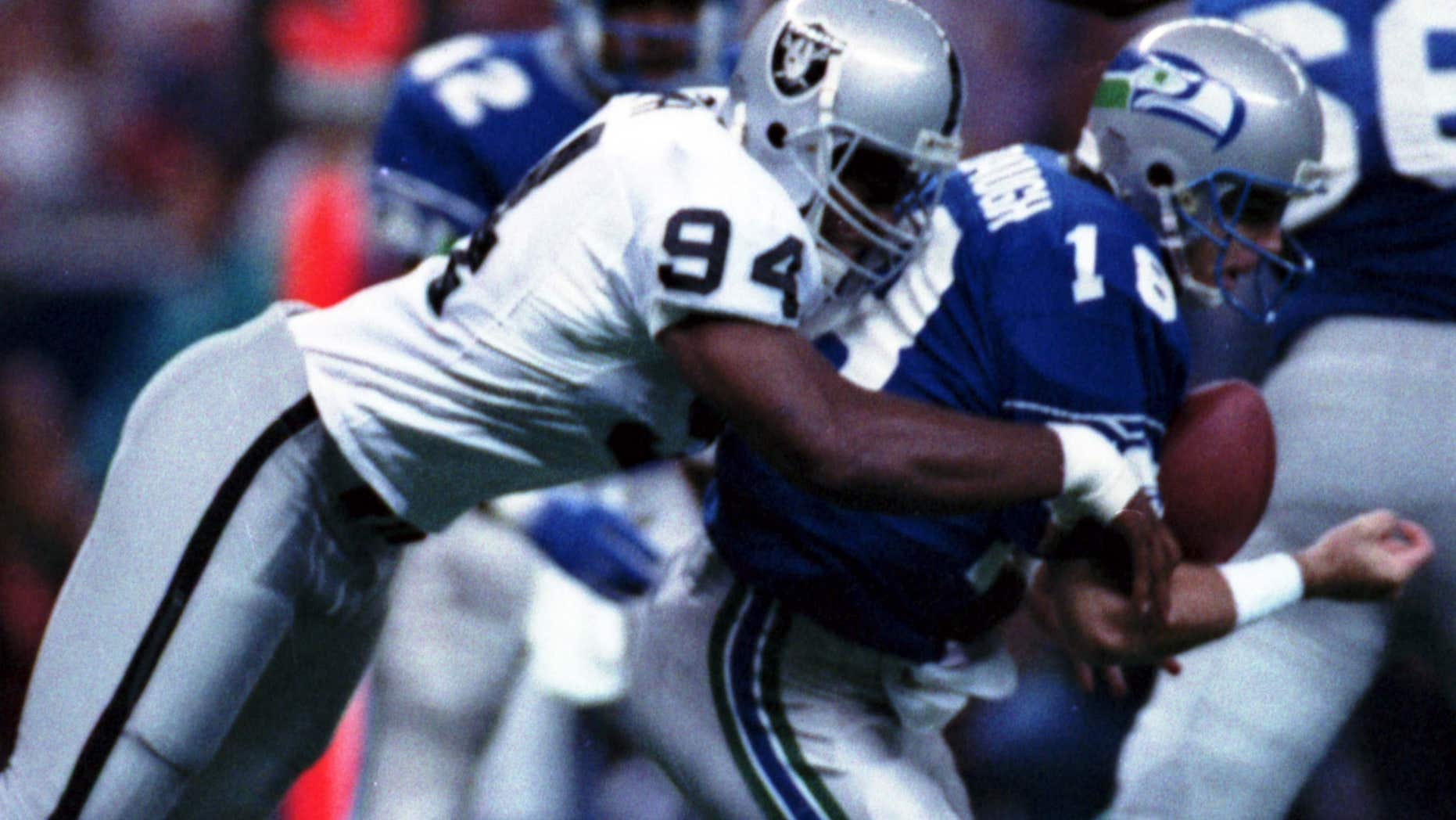 FILE - In this Oct. 18, 1992, file photo, Los Angeles Raiders' Anthony Smith (94) sacks Seattle Seahawks quarterback Stan Gelbaugh during the second quarter of an NFL football game in Seattle.