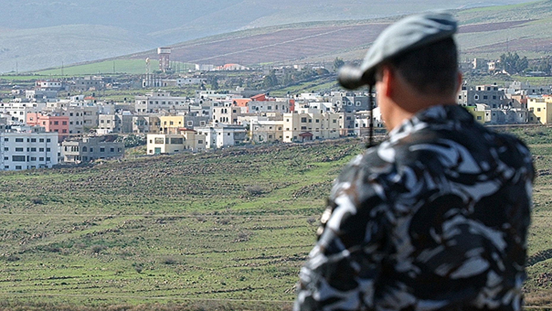 In this file photo taken on Jan. 3, 2006, a Lebanese security officer looks through binoculars at the Israeli part of the border village of Ghajar from the southern Lebanese village of Abbassiyeh in Lebanon.