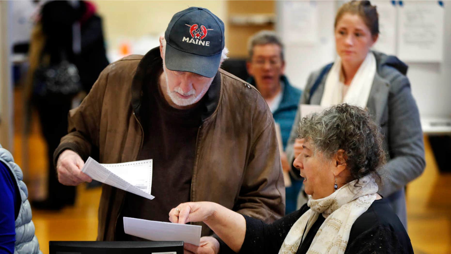 Michael Parent, left, gets instructions on submitting his ballots from warden Denise Shames while voting Tuesday, Nov. 7, 2017, in Portland, Maine.