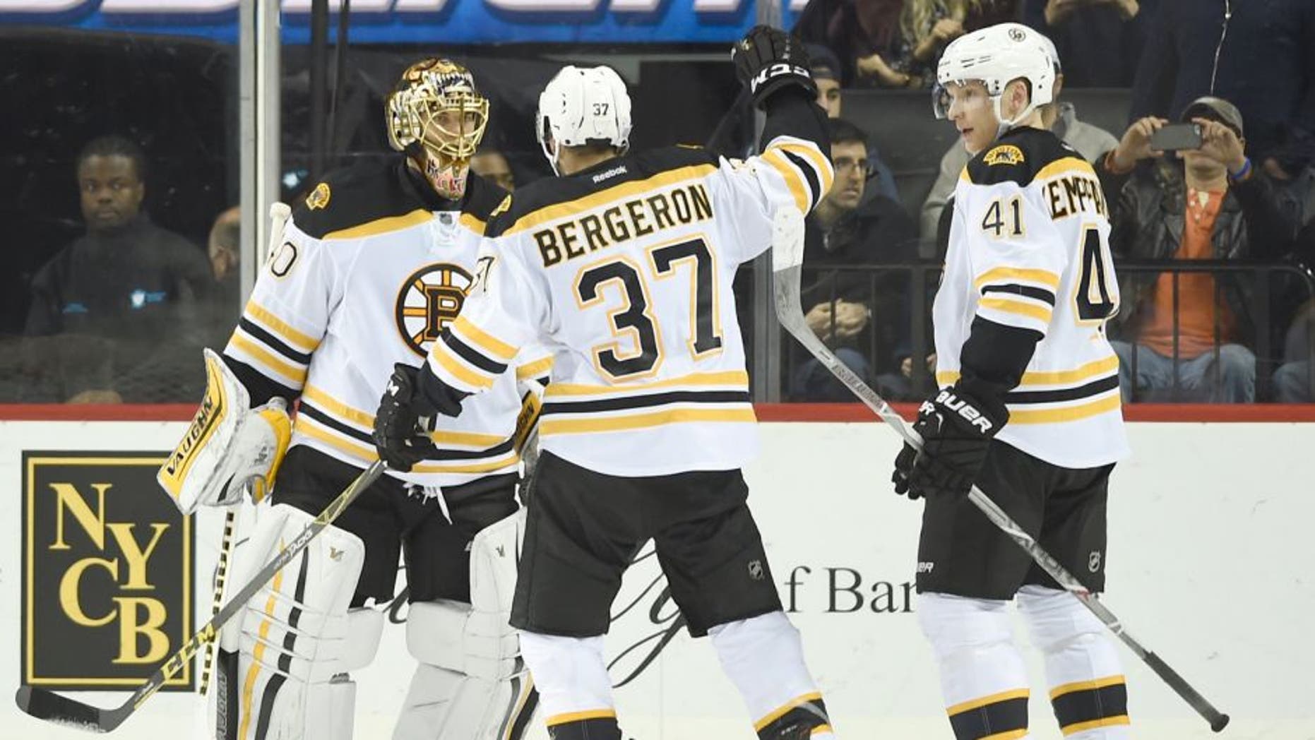 Boston Bruins goalie Tuukka Rask (40), center Patrice Bergeron (37) and left wing Joonas Kemppainen (41) celebrate their 2-1 win over the New York Islanders in an NHL hockey game on Sunday, Nov. 8, 2015, in New York. (AP Photo/Kathy Kmonicek)