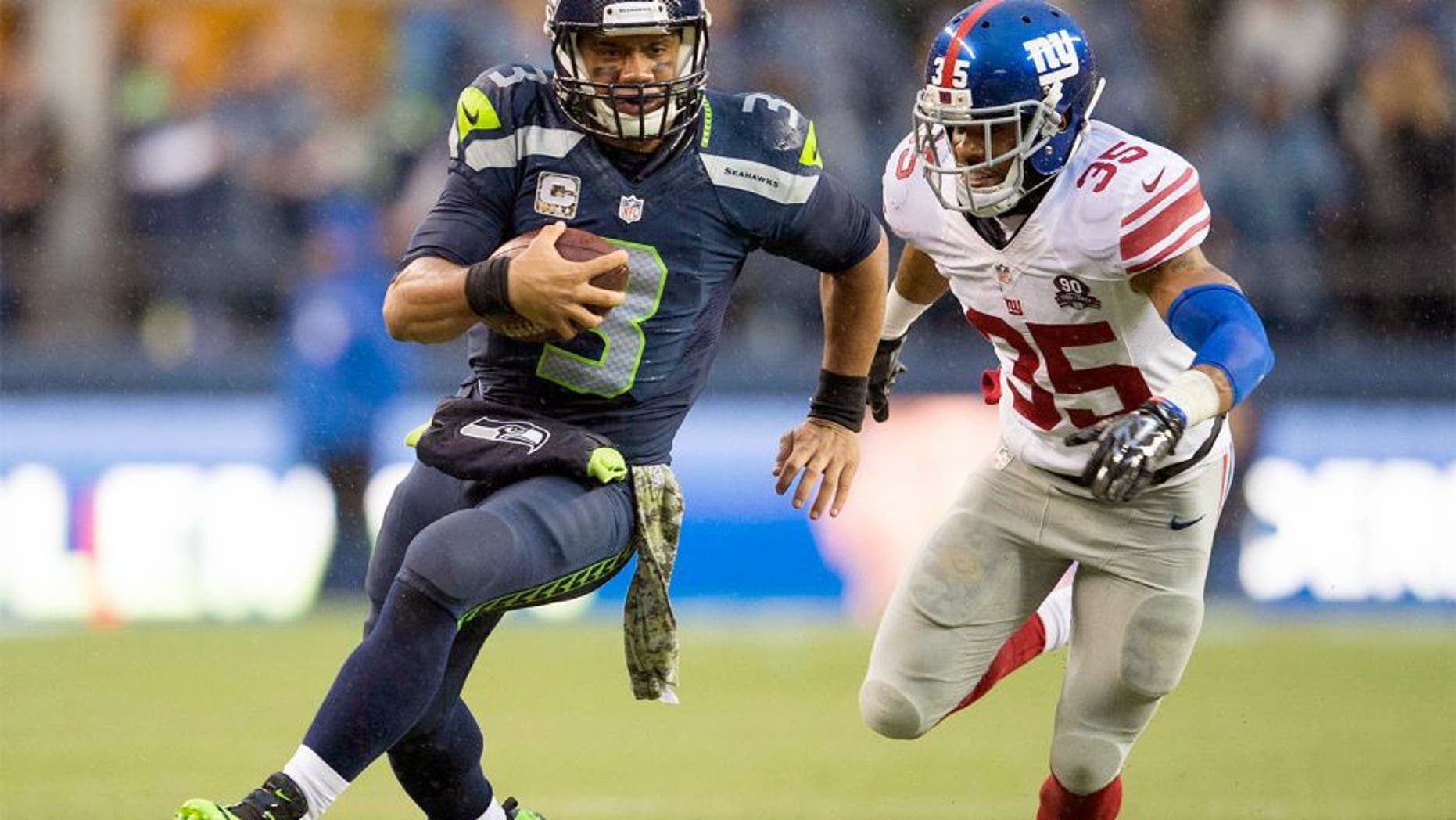 Nov 9, 2014; Seattle, WA, USA; Seattle Seahawks quarterback Russell Wilson (3) carries the ball while being chased by New York Giants free safety Quintin Demps (35) during the second half at CenturyLink Field. Seattle defeated New York 38-17. Mandatory Credit: Steven Bisig-USA TODAY Sports