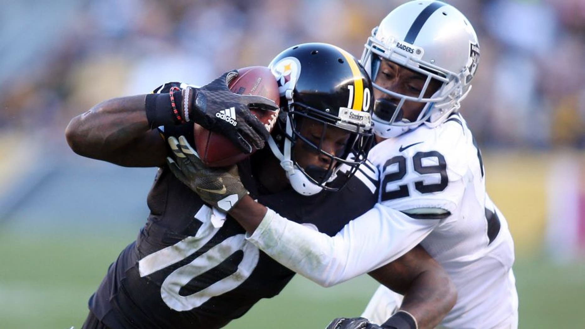 Nov 8, 2015; Pittsburgh, PA, USA; Pittsburgh Steelers wide receiver Martavis Bryant (10) secures the ball to his helmet after making a catch as Oakland Raiders cornerback David Amerson (29) defends during the third quarter at Heinz Field. The Steelers won 38-35. Mandatory Credit: Charles LeClaire-USA TODAY Sports
