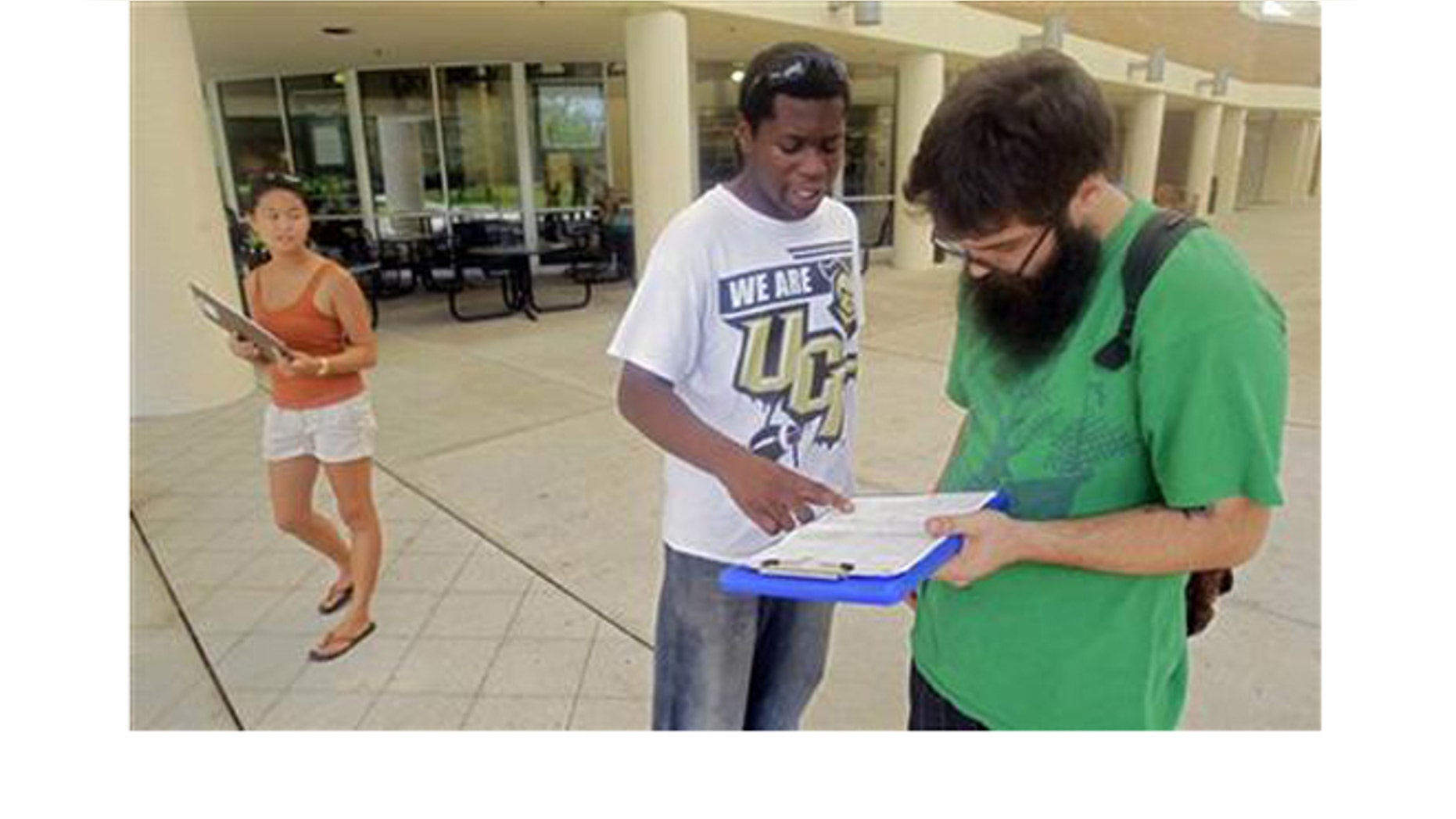 July 31, 2012: Aubrey Marks, left, watches Jordan Allen, center, as he helps student Casey Eirhstaedt, right, register to vote at the University of Central Florida in Orlando, Fla.