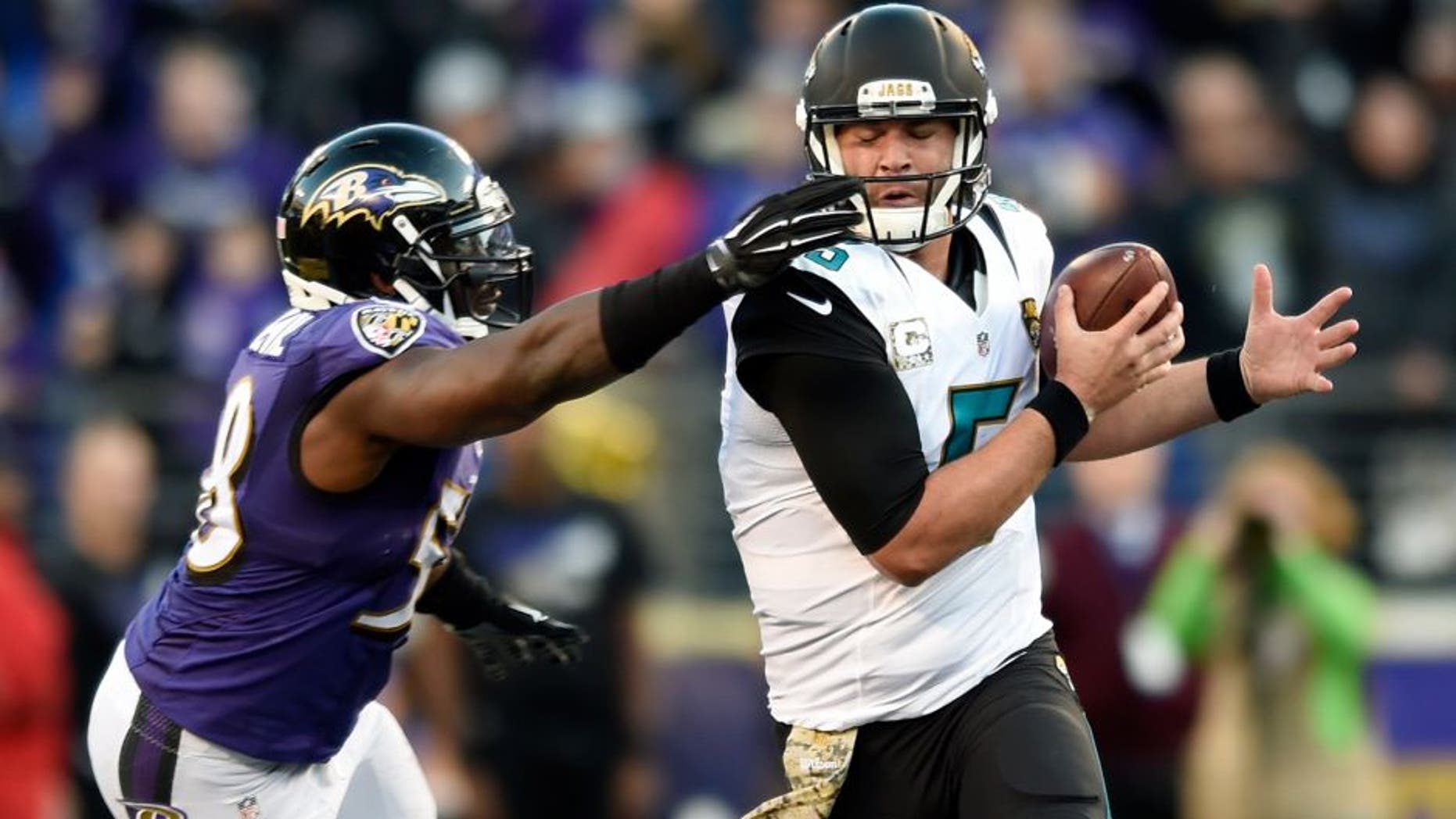 Baltimore Ravens outside linebacker Elvis Dumervil, left, grabs Jacksonville Jaguars quarterback Blake Bortles' face mask in the second half an NFL football game, Sunday, Nov. 15, 2015, in Baltimore. Jacksonville kicked the winning field goal after Baltimore received a face mask penalty on the play. Jacksonville won 22-20. (AP Photo/Gail Burton)