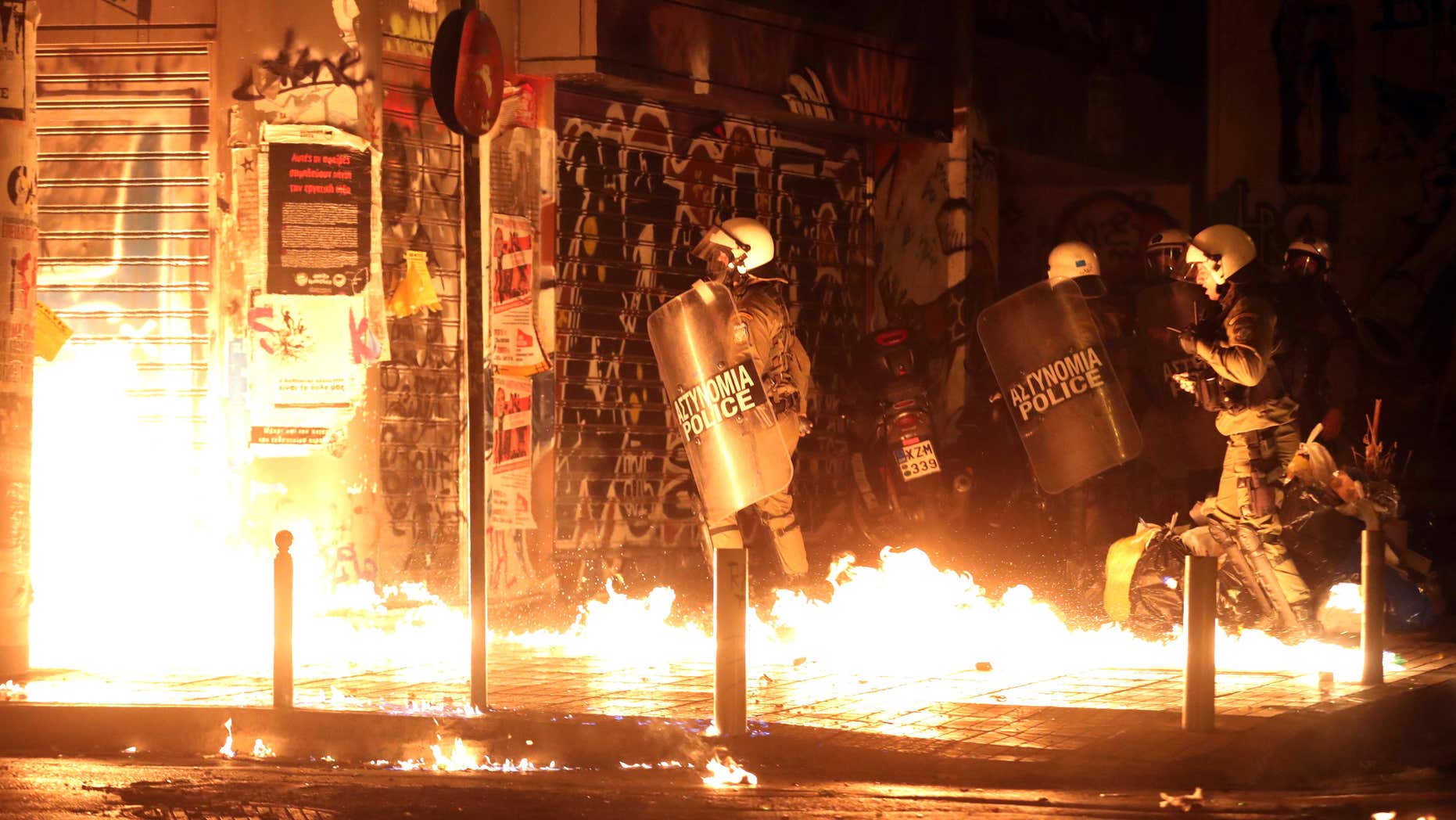 Nov. 15, 2016: Police officers walk past flames from a fire bomb thrown by demonstrators during a protest against the visit of US President Barack Obama in Athens.