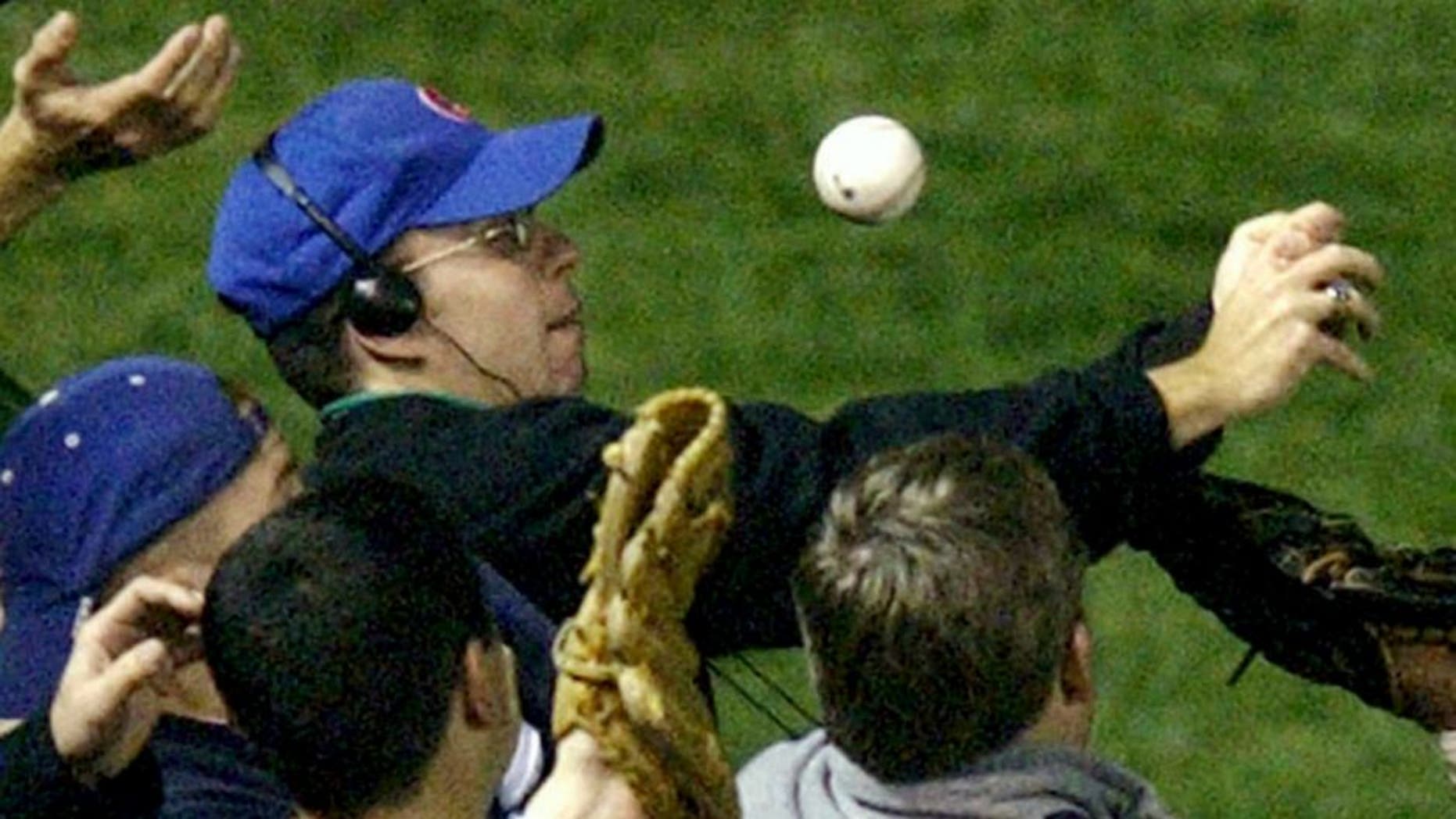 In this Oct 14, 2003 file photo, Steve Bartman catches a ball as Chicago Cubs left fielder Moises Alou's arm is seen reaching into the stands, at right, against the Florida Marlins in the eighth inning during Game 6 of the National League championship series Tuesday, Oct. 14, 2003, at Wrigley Field in Chicago. (AP Photo/Morry Gash) Steve Bartman