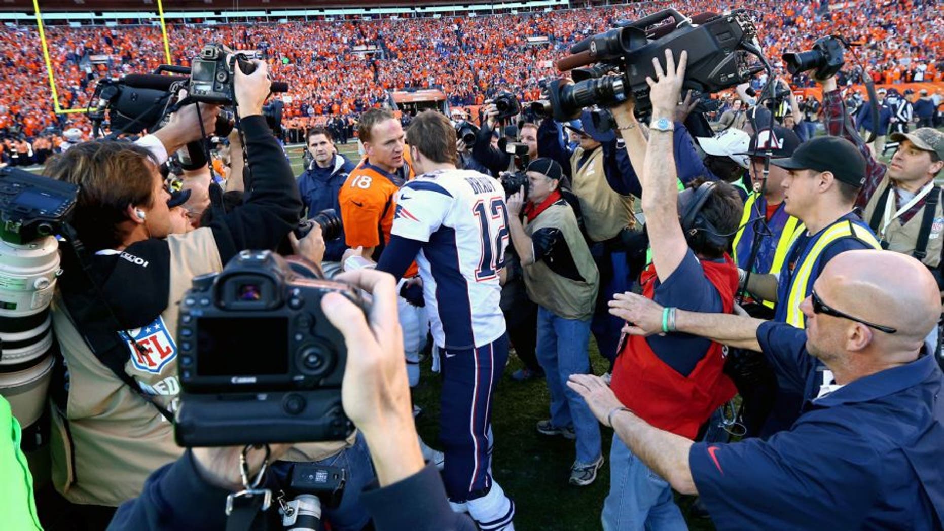 Jan 19, 2014; Denver, CO, USA; Members of the media fight for position to photograph Denver Broncos quarterback Peyton Manning shaking hands with New England Patriots quarterback Tom Brady following the 2013 AFC Championship football game at Sports Authority Field at Mile High. Mandatory Credit: Mark J. Rebilas-USA TODAY Sports
