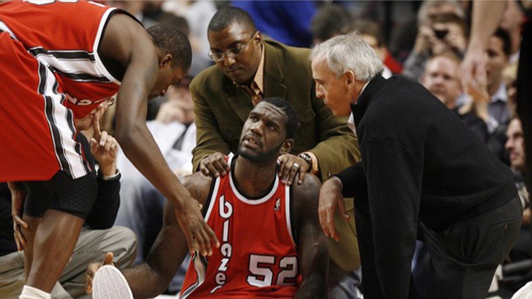 Portland Trail Blazers center Greg Oden (52) receives encouragement from teammate Martell Webster (L) as medical personel attend to his broken left leg during the first quarter of their NBA basketball game in Portland, Oregon on December 5, 2009.