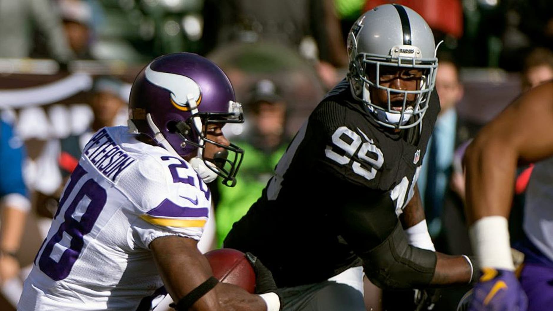 November 15, 2015; Oakland, CA, USA; Minnesota Vikings running back Adrian Peterson (28) runs with the football against Oakland Raiders outside linebacker Aldon Smith (99) during the first quarter at O.co Coliseum. Mandatory Credit: Kyle Terada-USA TODAY Sports