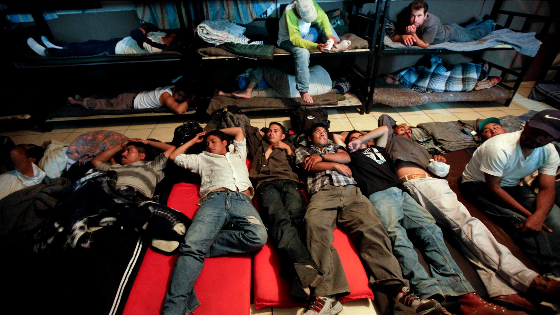 FILE - In this April 28, 2010, file photo, men look for a place to sleep in a crowded shelter for migrants deported from the United States, in the border city of Nogales, Mexico.
