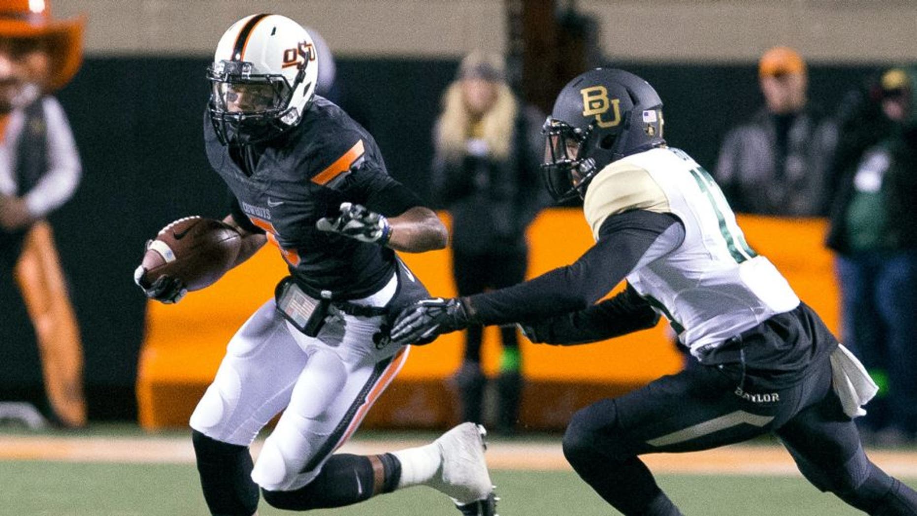 Nov 23, 2013; Stillwater, OK, USA; Oklahoma State Cowboys wide receiver Josh Stewart (5) runs the ball during the first quarter against Baylor Bears safety Terrell Burt (13) at Boone Pickens Stadium. Mandatory Credit: Richard Rowe-USA TODAY Sports