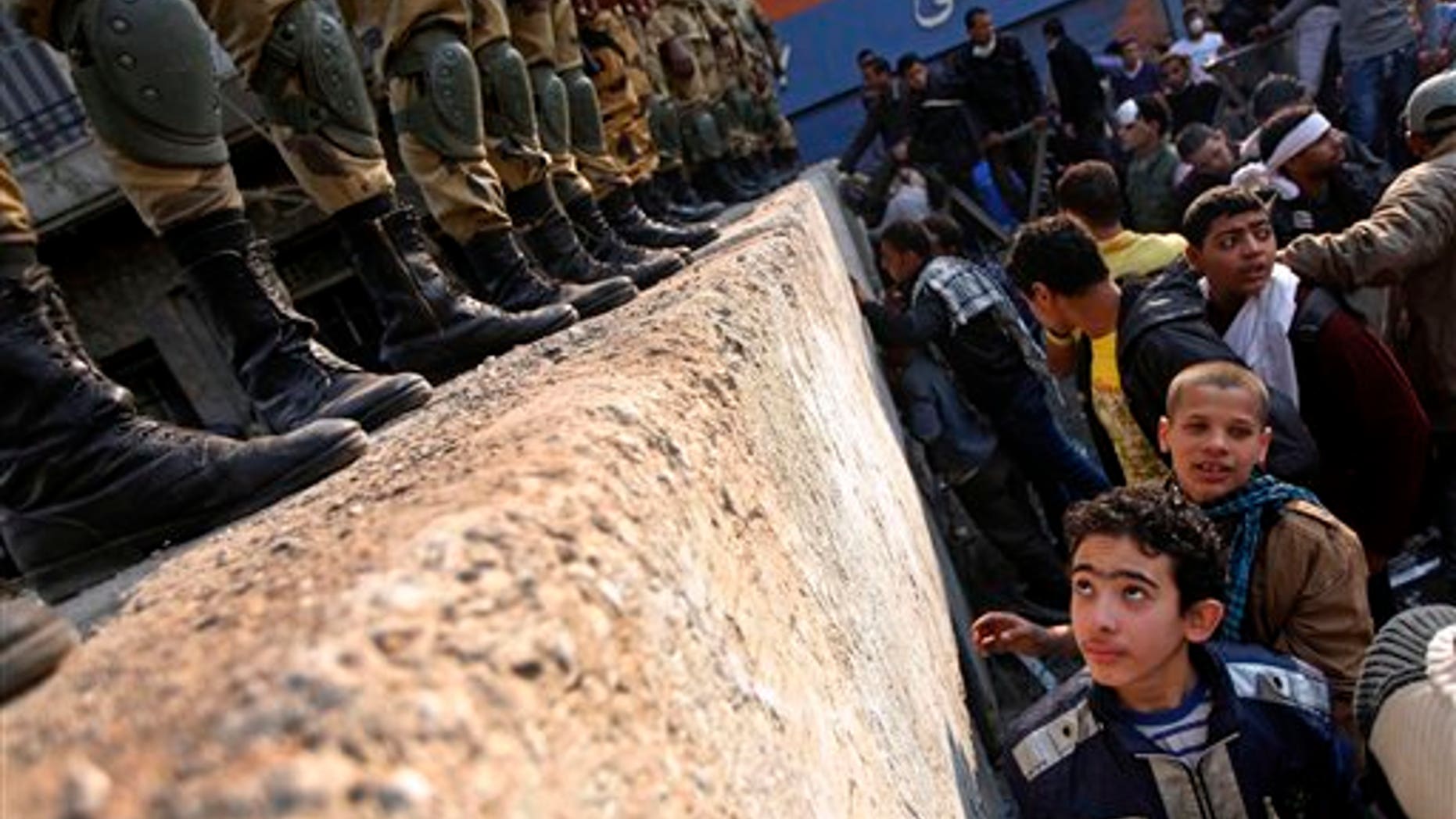 November 24, 2011: A boy looks at Egyptian Army soldiers standing guard atop a concrete block barricade on the street between Tahrir Square and the interior ministry in Cairo, Egypt.