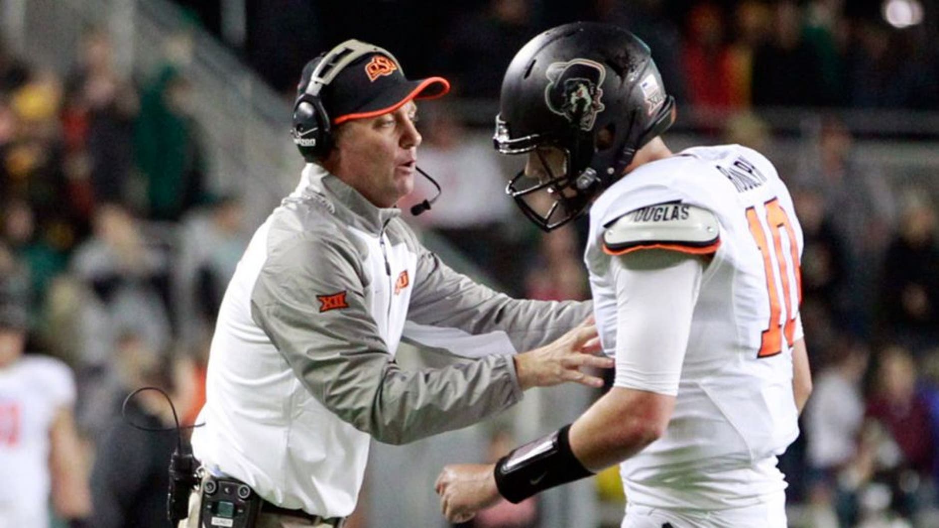 Nov 22, 2014; Waco, TX, USA; Oklahoma State Cowboys head coach Mike Gundy talks with quarterback Mason Rudolph (10) during a time out in the second quarter against the Baylor Bears at McLane Stadium. Mandatory Credit: Tim Heitman-USA TODAY Sports