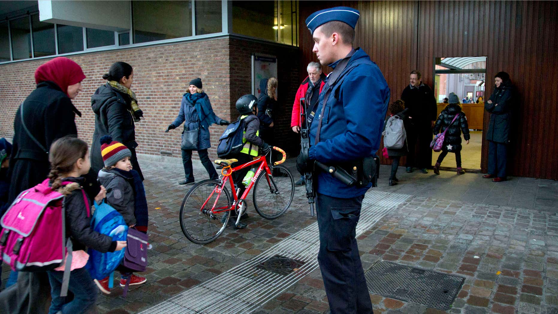 Nov. 25, 2015: Children pass a police officer as they arrive for school in the center of Brussels.