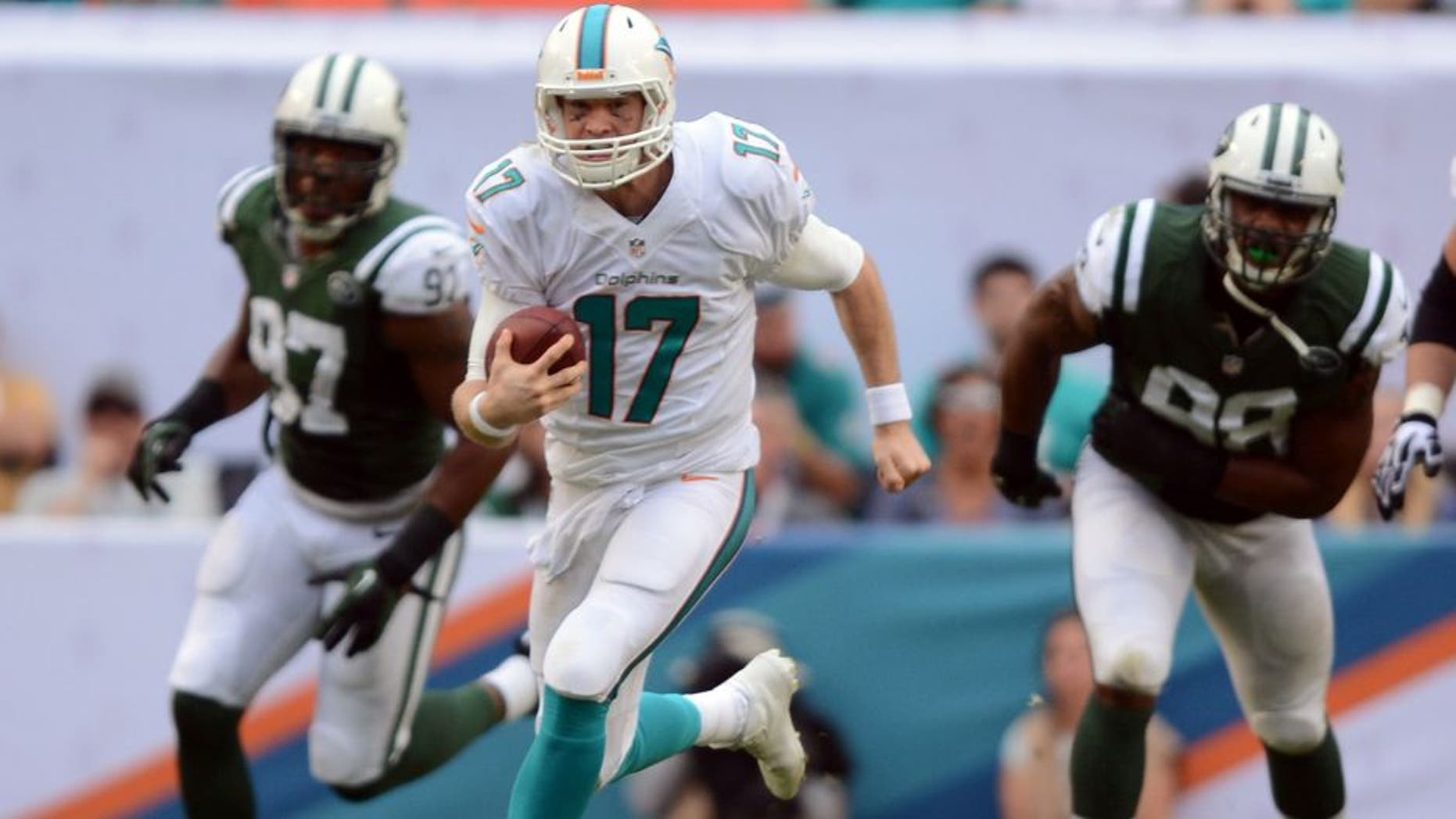 Dec 29, 2013; Miami Gardens, FL, USA; Miami Dolphins quarterback Ryan Tannehill (17) breaks free as New York Jets outside linebacker Calvin Pace (97) and linebacker Quinton Coples (98) chase during the second half of the game at Sun Life Stadium. The Jets defeated Miami 20-7. Mandatory Credit: Brad Barr-USA TODAY Sports