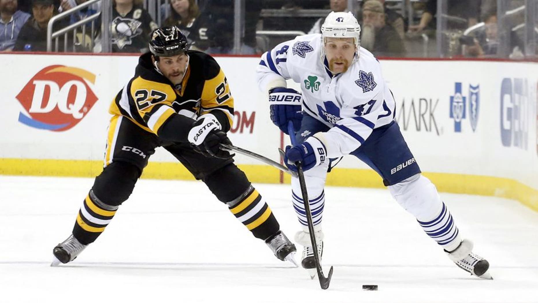 Nov 26, 2014; Pittsburgh, PA, USA; Pittsburgh Penguins right wing Craig Adams (27) and Toronto Maple Leafs center Leo Komarov (47) chase the puck during the third period at the CONSOL Energy Center. The Penguins won 4-3 in overtime. Mandatory Credit: Charles LeClaire-USA TODAY Sports