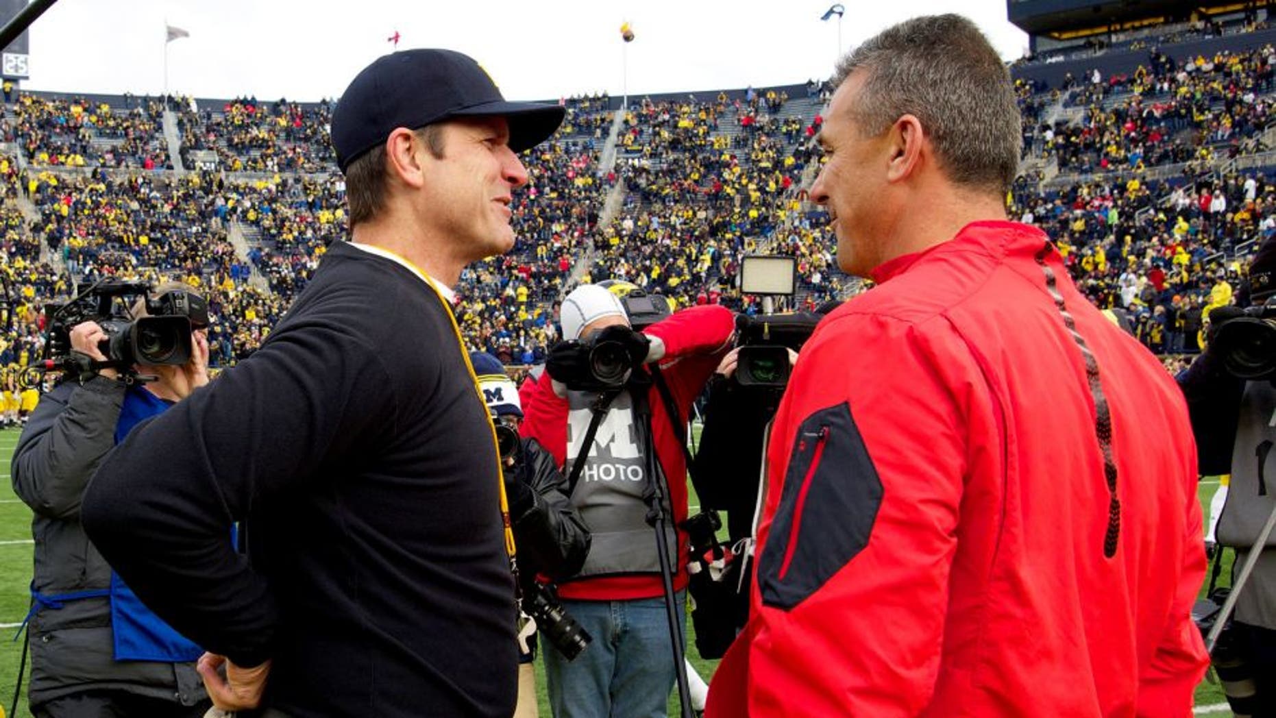 Michigan head coach Jim Harbaugh, left, talks with Ohio State head coach Urban Meyer, right, on the Michigan Stadium field before an NCAA college football game in Ann Arbor, Mich., Saturday, Nov. 28, 2015. (AP Photo/Tony Ding)