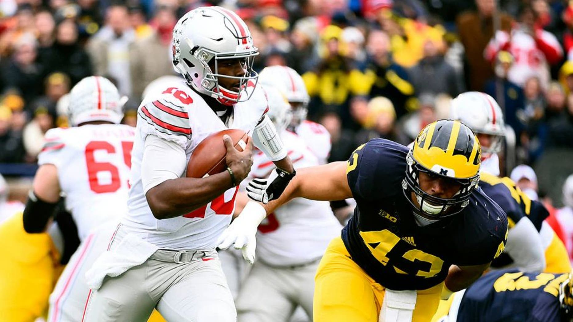 Nov 28, 2015; Ann Arbor, MI, USA; Ohio State Buckeyes quarterback J.T. Barrett (16) runs the ball Michigan Wolverines defensive end Chris Wormley (43) over to defend in the first quarter at Michigan Stadium. Mandatory Credit: Tim Fuller-USA TODAY Sports