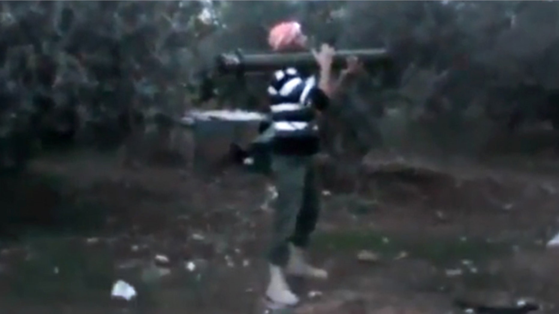 Nov. 27, 2012: In this image taken from video obtained from the Ugarit News, which has been authenticated based on its contents and other AP reporting, a Free Syrian Army fighter fires his weapon toward a military tank, unseen, in Daraa, Syria.