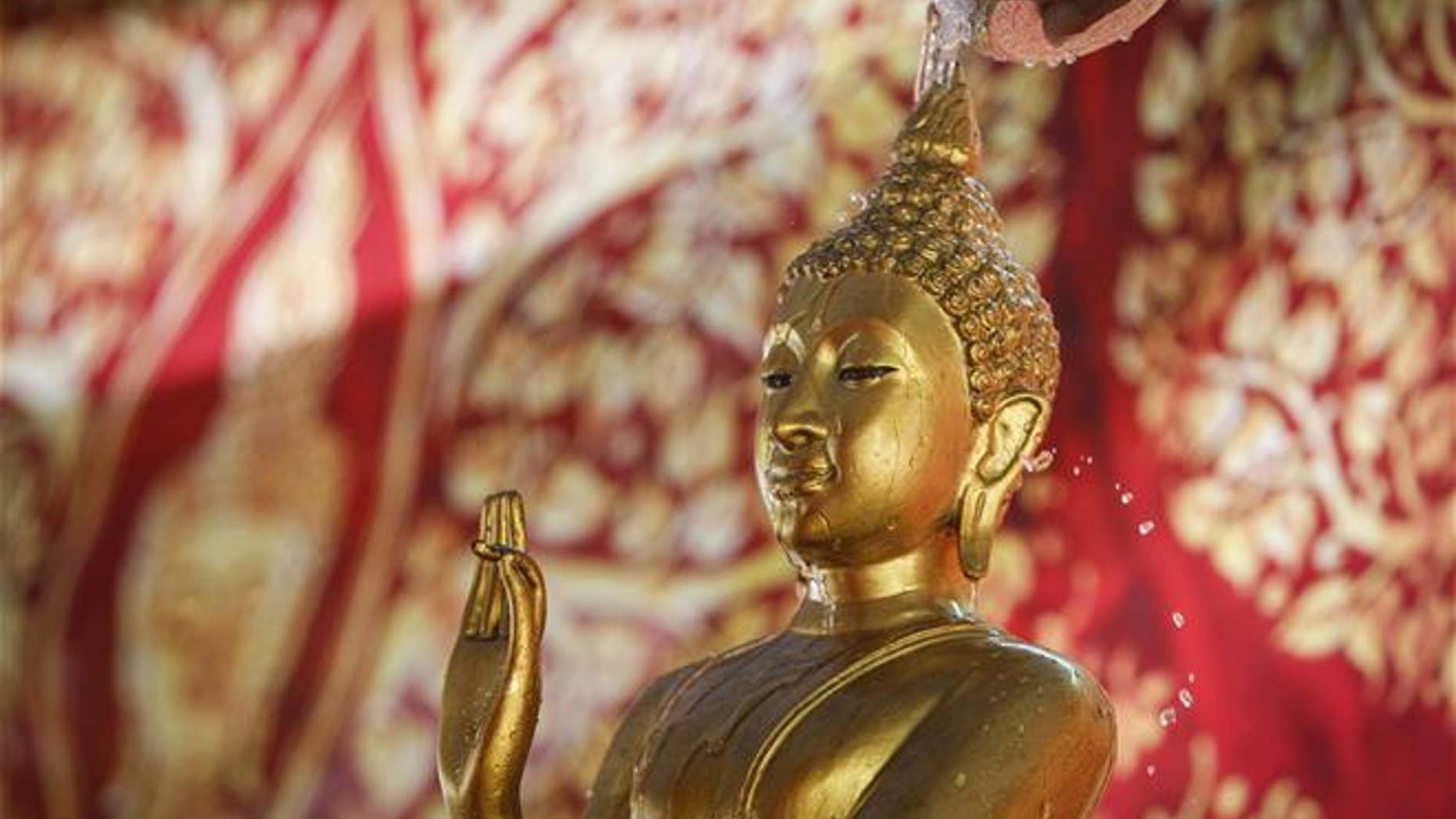 A Buddha statue is showered by a devotee during a bathing ritual in Kuala Lumpur, Malaysia, on May 21, 2016.