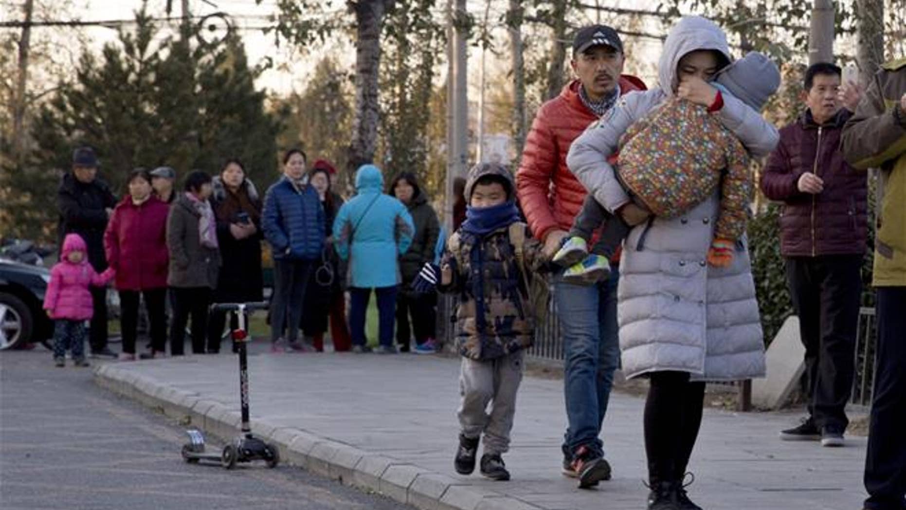 A woman carries a child as they arrive at the RYB Kindergarten in Beijing on Friday.