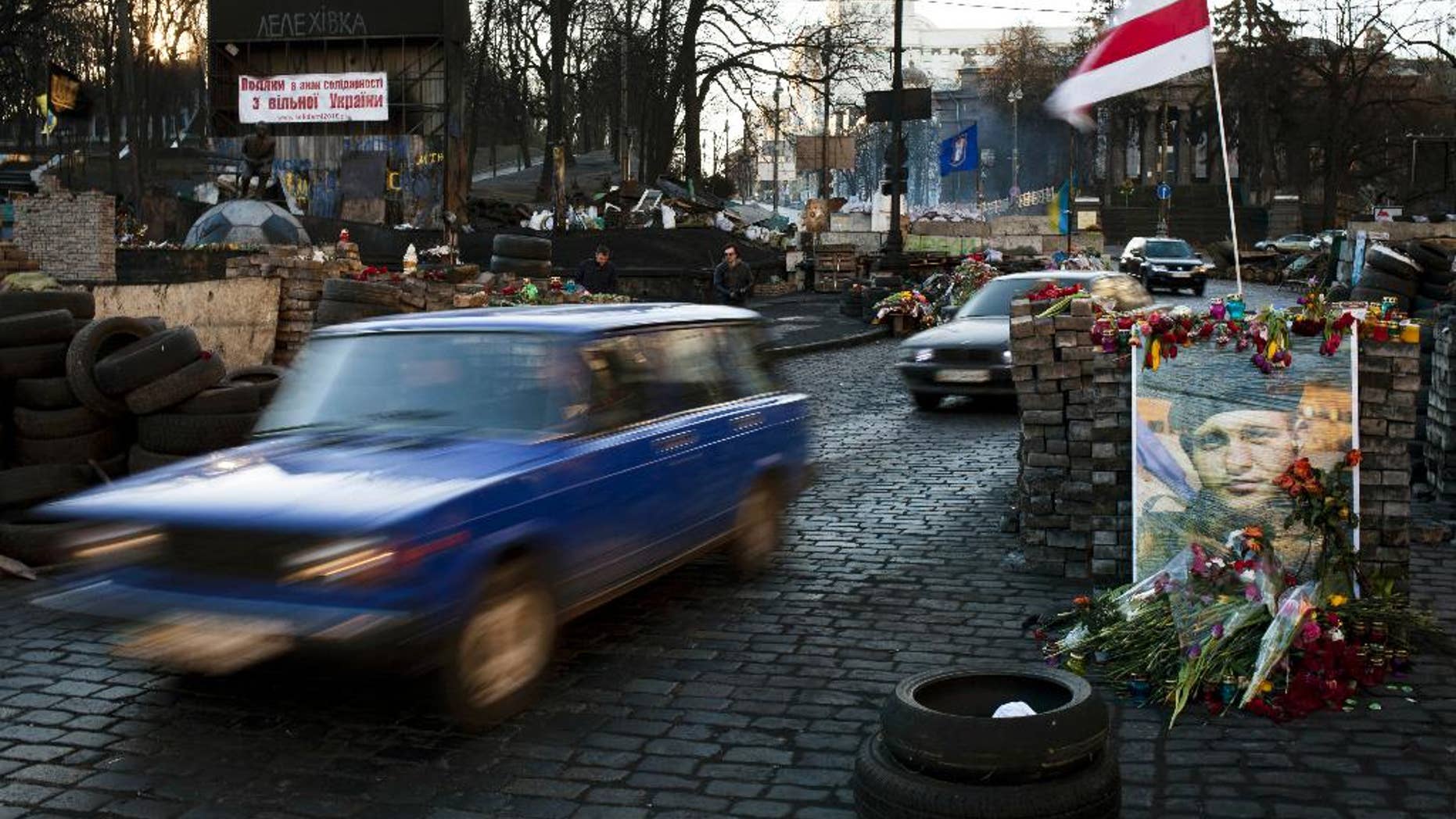 Cars make their way past barricades placed on a road near the Dynamo Kyiv soccer club stadium in Kiev, Ukraine, Wednesday, March 12, 2014. (AP Photo/David Azia)