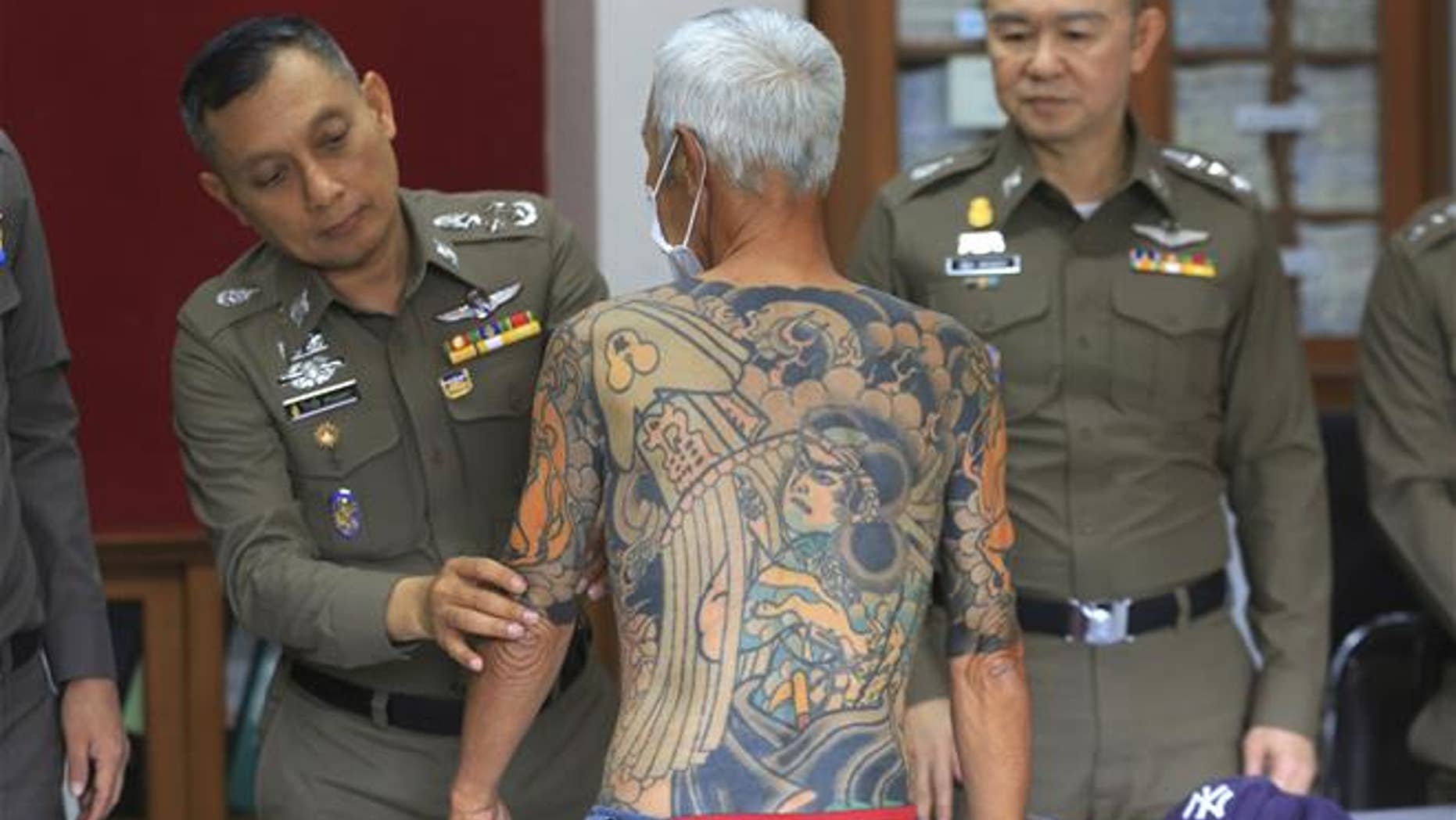 Japanese gang member Shigeharu Shirai displays his tattoos at a police station during a press conference in Lopburi.