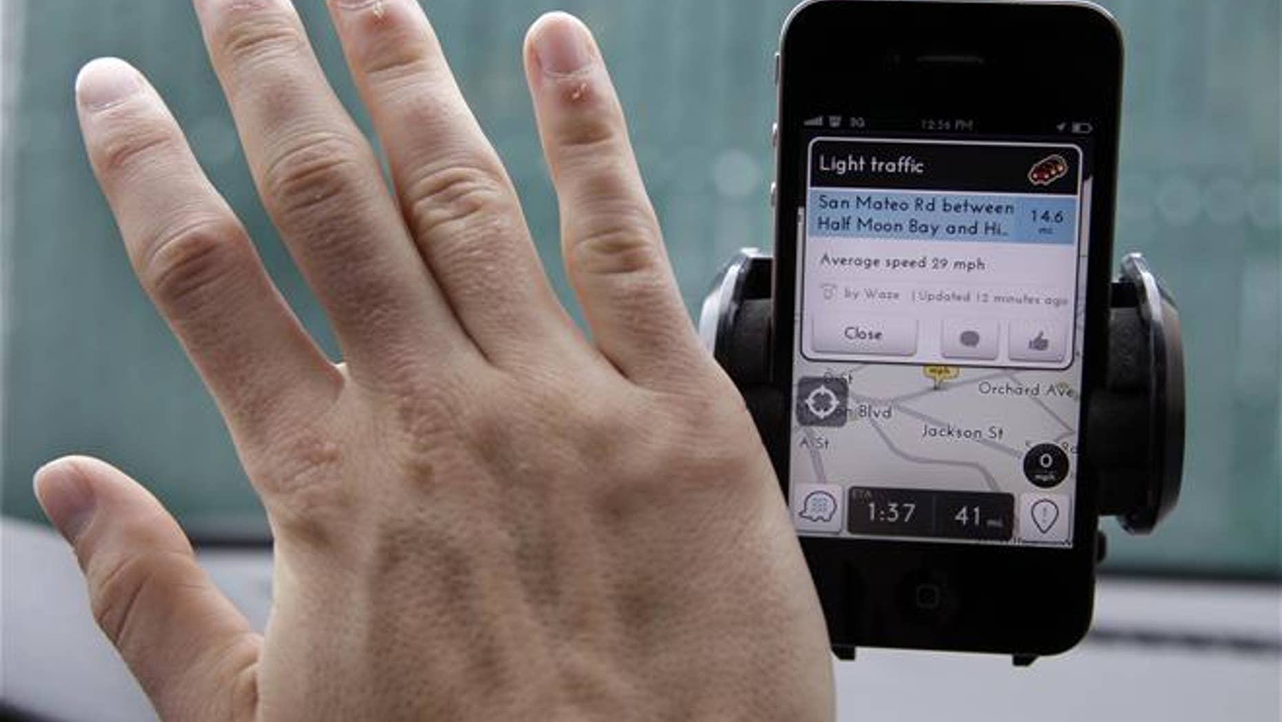 In this March 15, 2012, file photo, a user waves his hand over the Waze traffic and navigation app on his Apple iPhone in a Menlo Park, Calif., parking lot.
