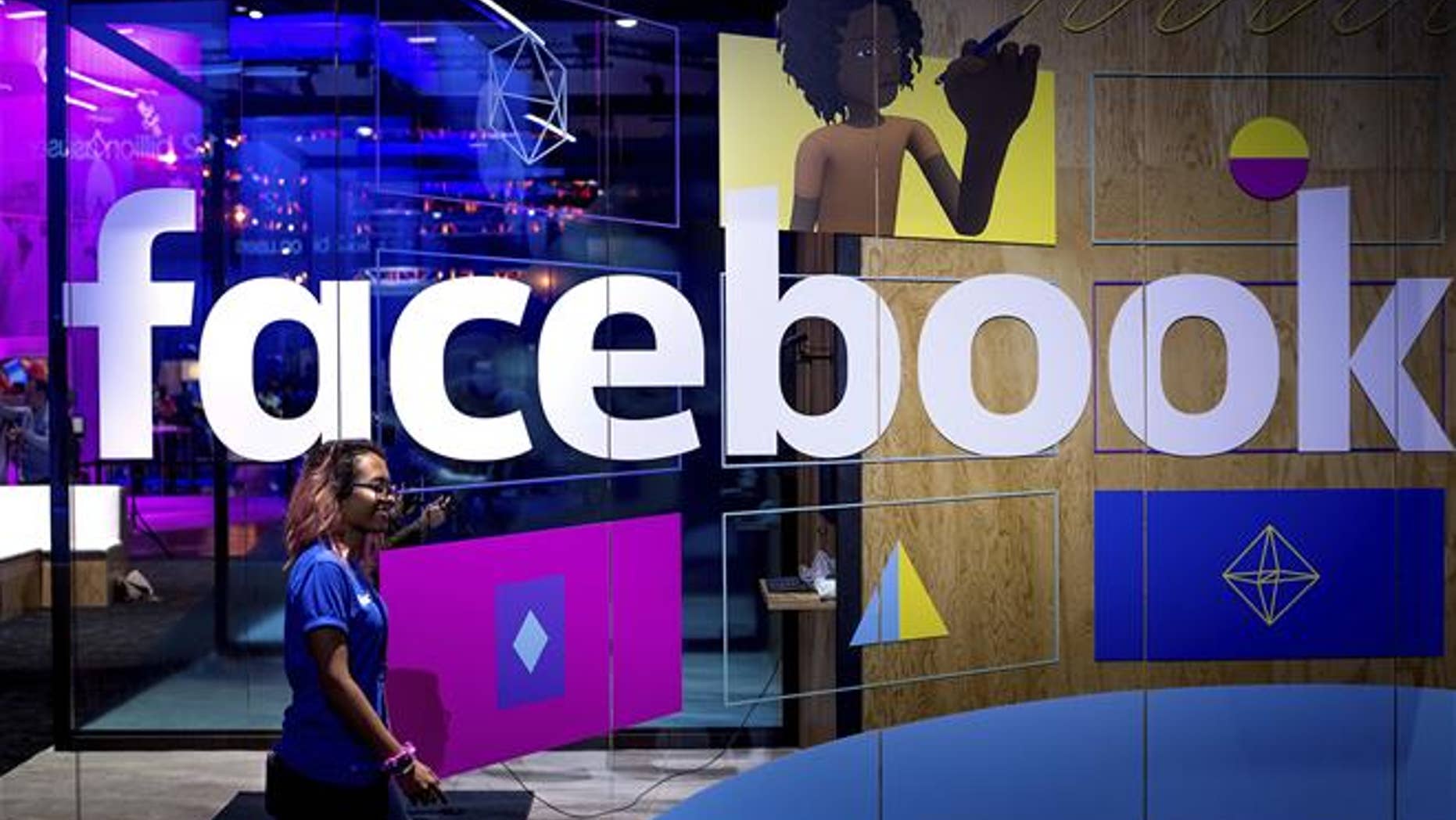 In this Tuesday, April 18, 2017, file photo, a conference worker passes a demo booth at Facebook's annual F8 developer conference, in San Jose, Calif. Facebook Inc. reports earnings Wednesday, Jan. 31, 2018.