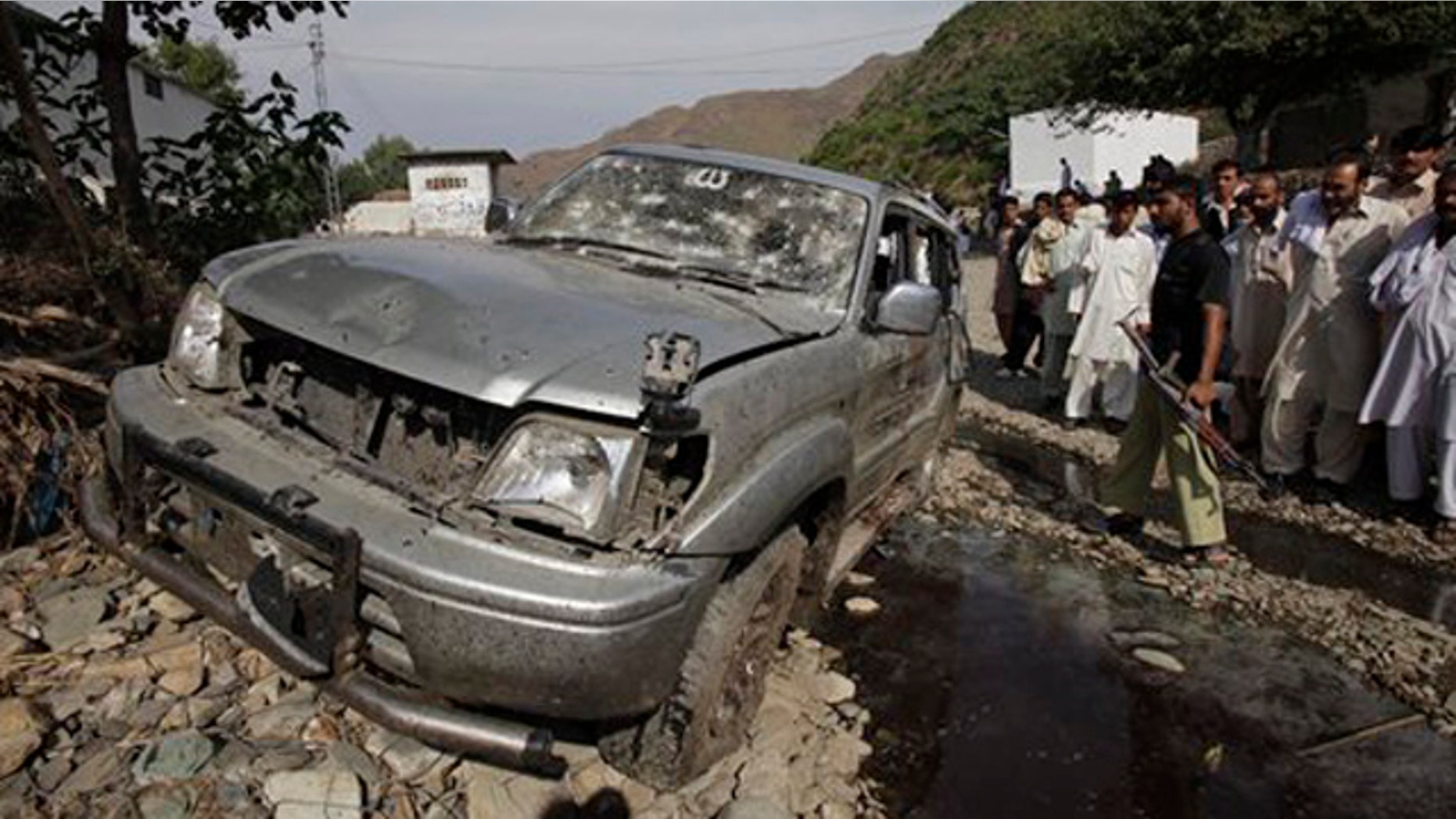 November 8, 2011: People look at a vehicle targeted by a suicide attacker in Swabi near Peshawar, Pakistan.
