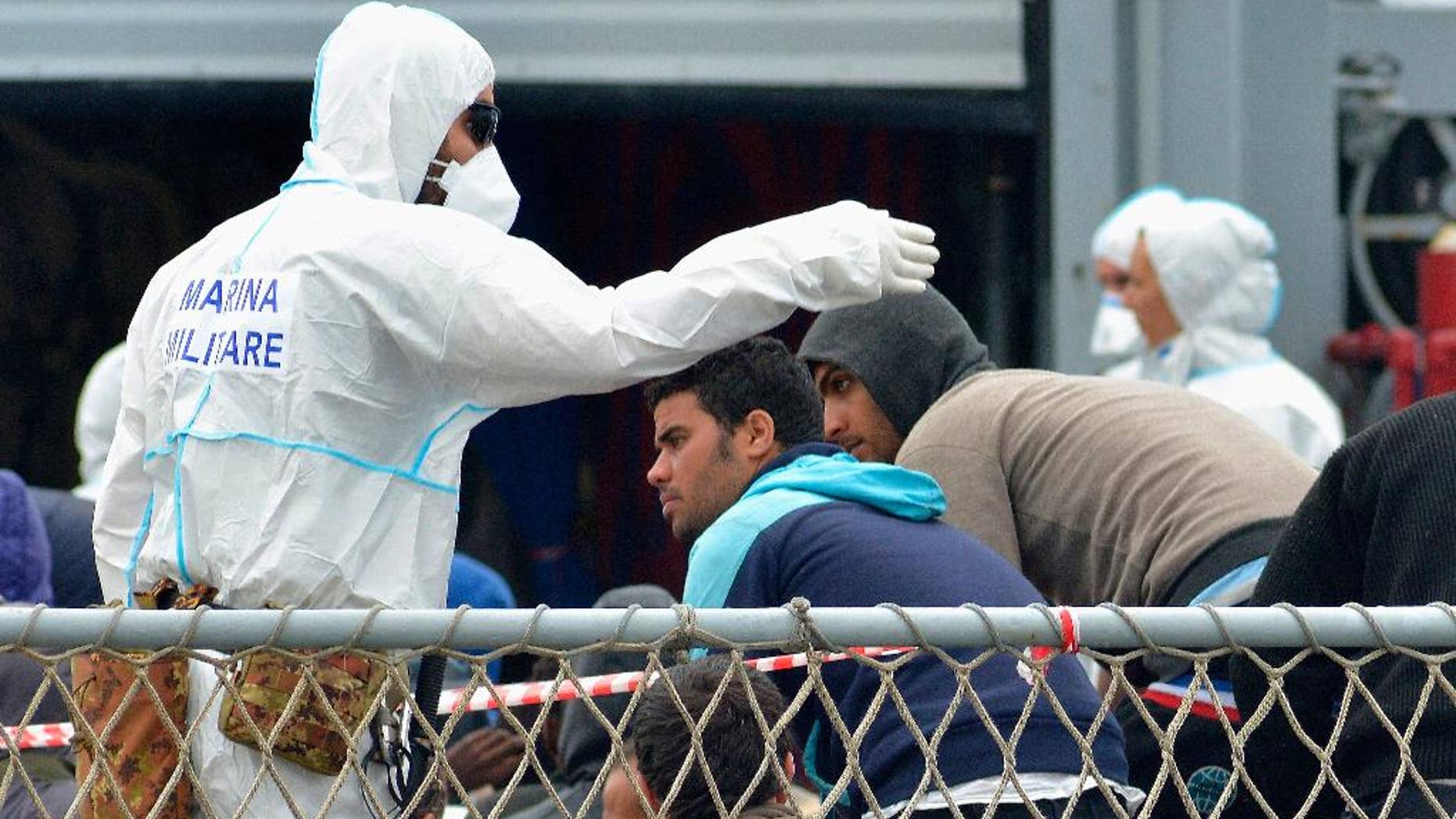 In this photo released by Greek Defense Ministry on April 27, 2015, Defense Minister Panos Kammenos, left, awards Army Sgt. Antonis Deligiorgis, the Cross of Excellency for his role in rescuing passengers on a ship carrying migrants on the island of Rhodes, at a ceremony in Athens on April 27, 2015. Deligiogis was photographed assisting Eritrean asylum seeker Wegasi Nebiat, in an image that was on front pages of leading world newspapers the following day. Three people died in the shipwreck, while 90 others from Syria and Eritrea were rescued. (Greek Defense Ministry via AP)