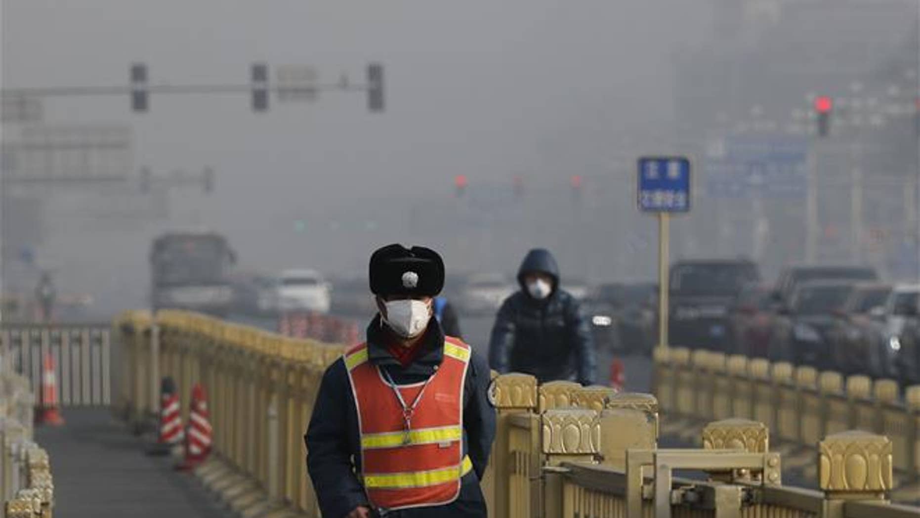 A traffic warden wearing a protection mask walks on a street near Tiananmen Square in Beijing as the capital of China is blanketed by heavy smog in this file photo.