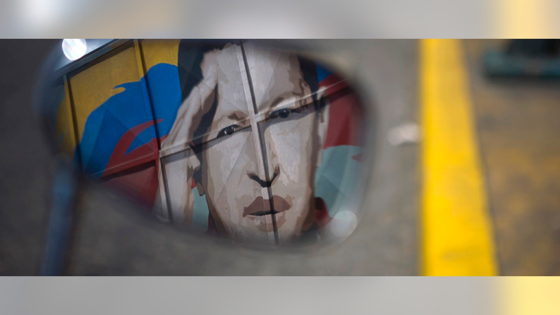 June 29: A motorcycle mirror reflects a painting depicting Venezuela's President Hugo Chavez in Caracas, Venezuela.AP Photo/Ariana Cubillos)