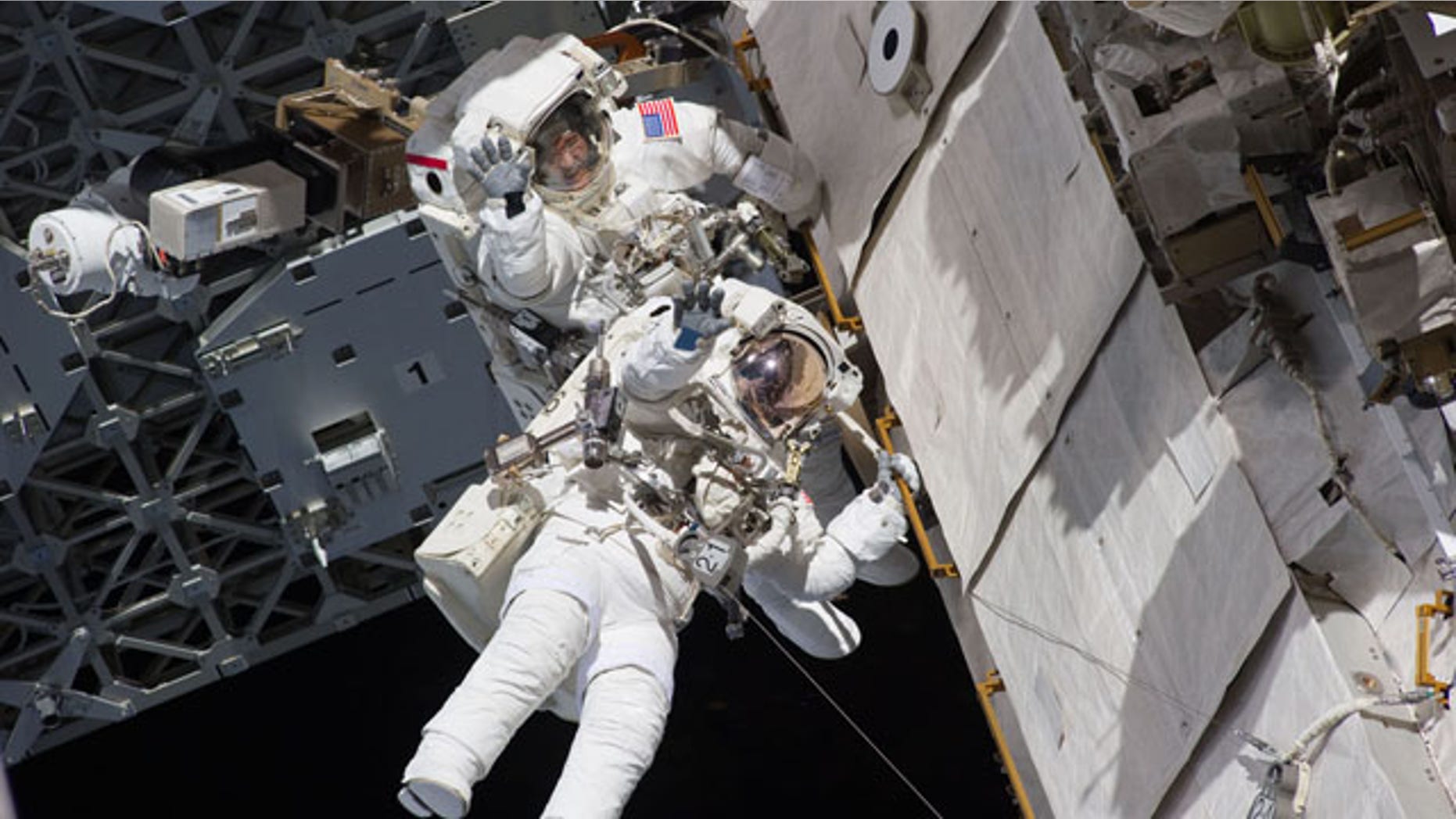 Astronauts Steve Bowen and Alvin Drew wave during the first spacewalk of their STS-133 mission on Feb. 28, 2011 while working outside the International Space Station during the final flight of space shuttle Discovery.