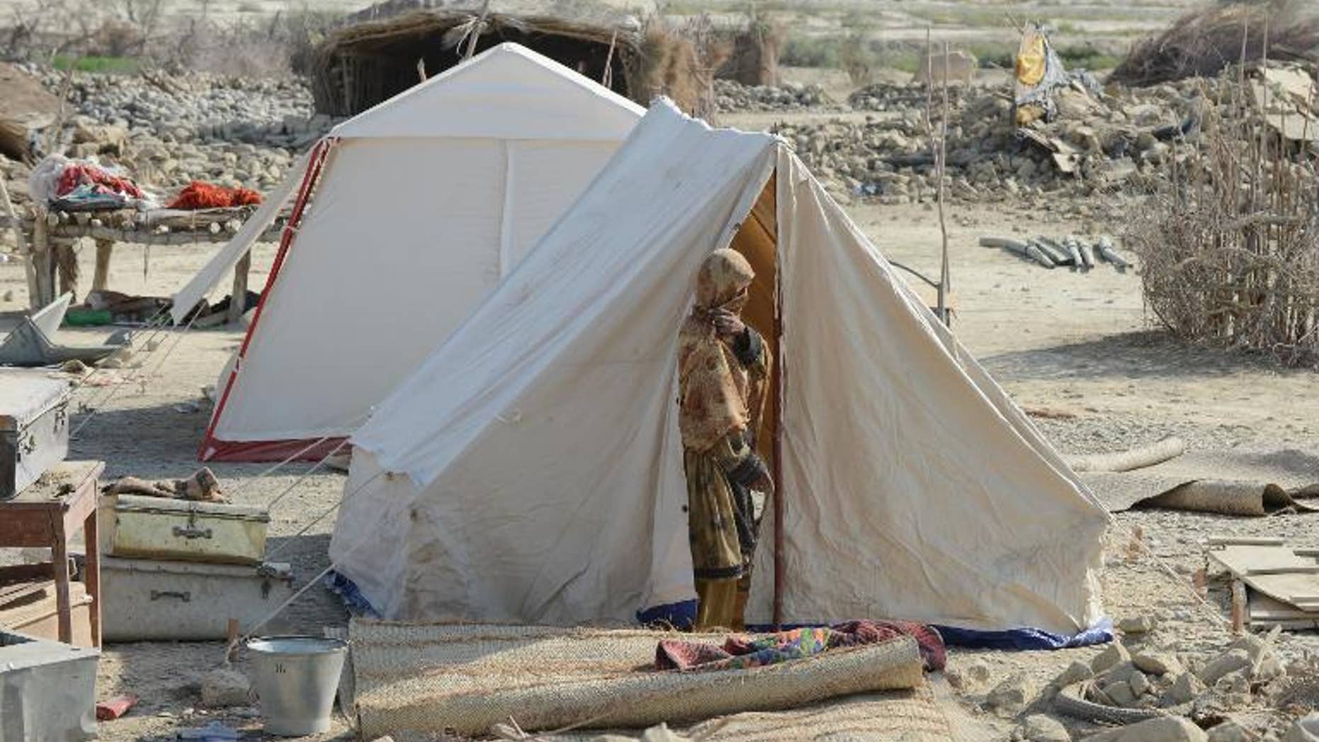 A Pakistani earthquake survivor stands outside her tent near collapsed mud houses in the Dhall Bedi Peerander area of the earthquake-devastated district of Awaran on September 27, 2013