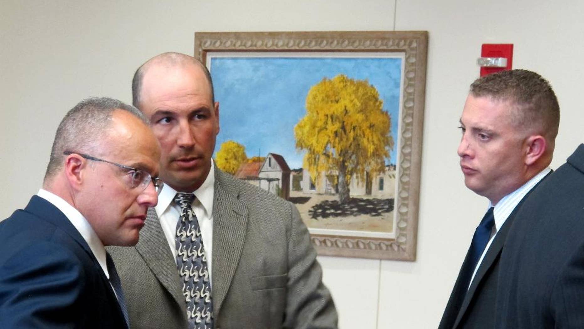 This Tuesday, Aug. 18, 2015 photo, former Albuquerque detective Keith Sandy, left, and Albuquerque officer Dominique Perez, right, talk to defense lawyer Sam Bregman, center, before a preliminary hearing begins in Albuquerque, N.M. A judge ruled Tuesday that Perez and Sandy must stand trial for the fatal shooting of a homeless man in 2014 but experts say it will be difficult to get convictions. (AP Photo/Russell Contreras)