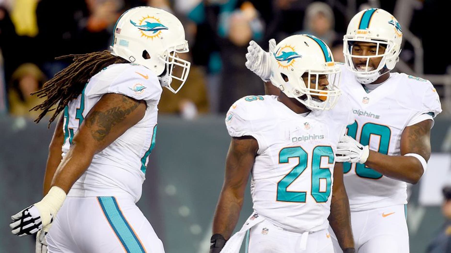EAST RUTHERFORD, NJ - DECEMBER 01: Lamar Miller #26 of the Miami Dolphins celebrates with teammates Dallas Thomas #63 and Dion Sims #80 after scoring a 4 yard touchdown in the fourth quarter to tie the game against the New York Jets at MetLife Stadium on December 1, 2014 in East Rutherford, New Jersey. (Photo by Alex Goodlett/Getty Images)