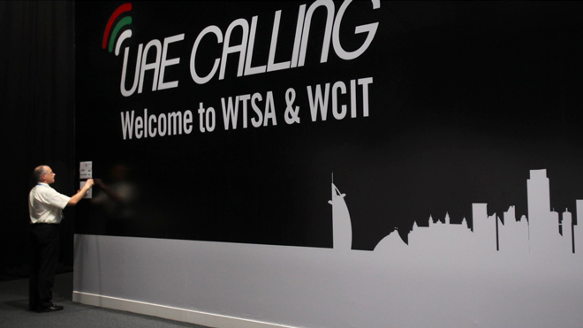 Dec. 3, 2012: An official sticks a note on the wall next to the conference banner during the eleventh day of the World Conference on International Telecommunication in Dubai, United Arab Emirates.