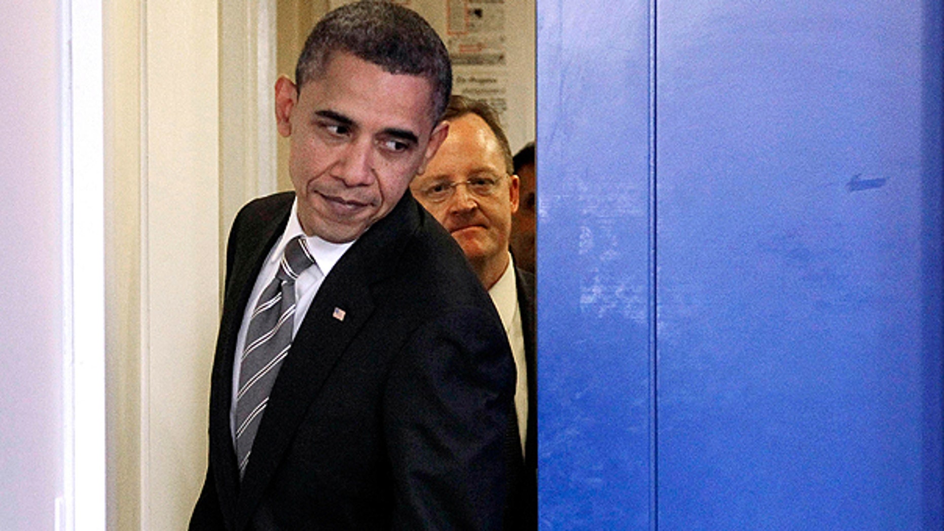 Dec. 7: President Obama, followed by White House Press Secretary Robert Gibbs, slides past the pocket door to the briefing room as he walks out to begin his news conference at the White House in Washington.