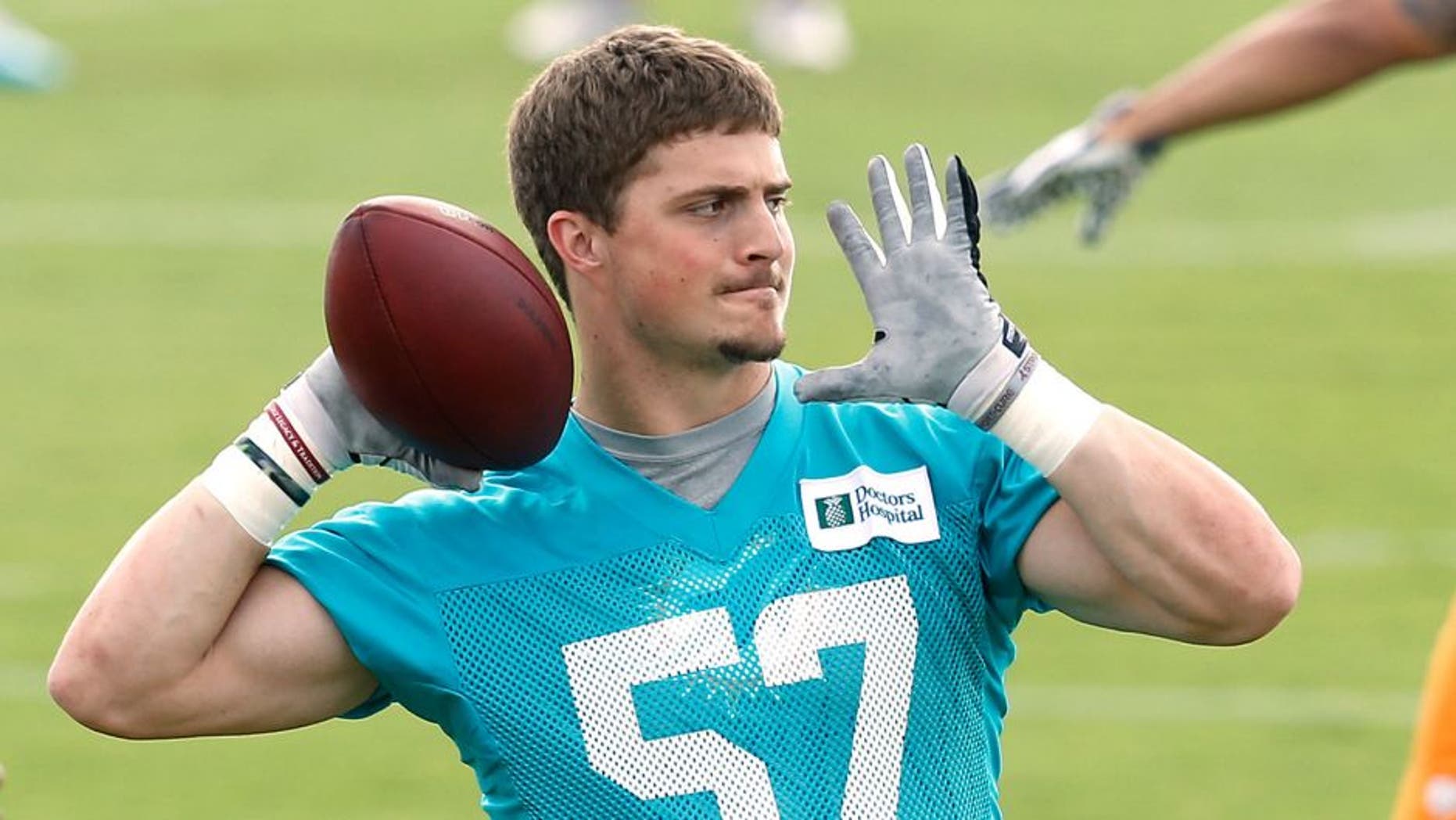 DAVIE, FL - MAY 27: Jordon Tripp #57 of the Miami Dolphins throws the ball during the teams first OTA on May 27, 2014 at the Miami Dolphins training facility in Davie, Florida. (Photo by Joel Auerbach/Getty Images)