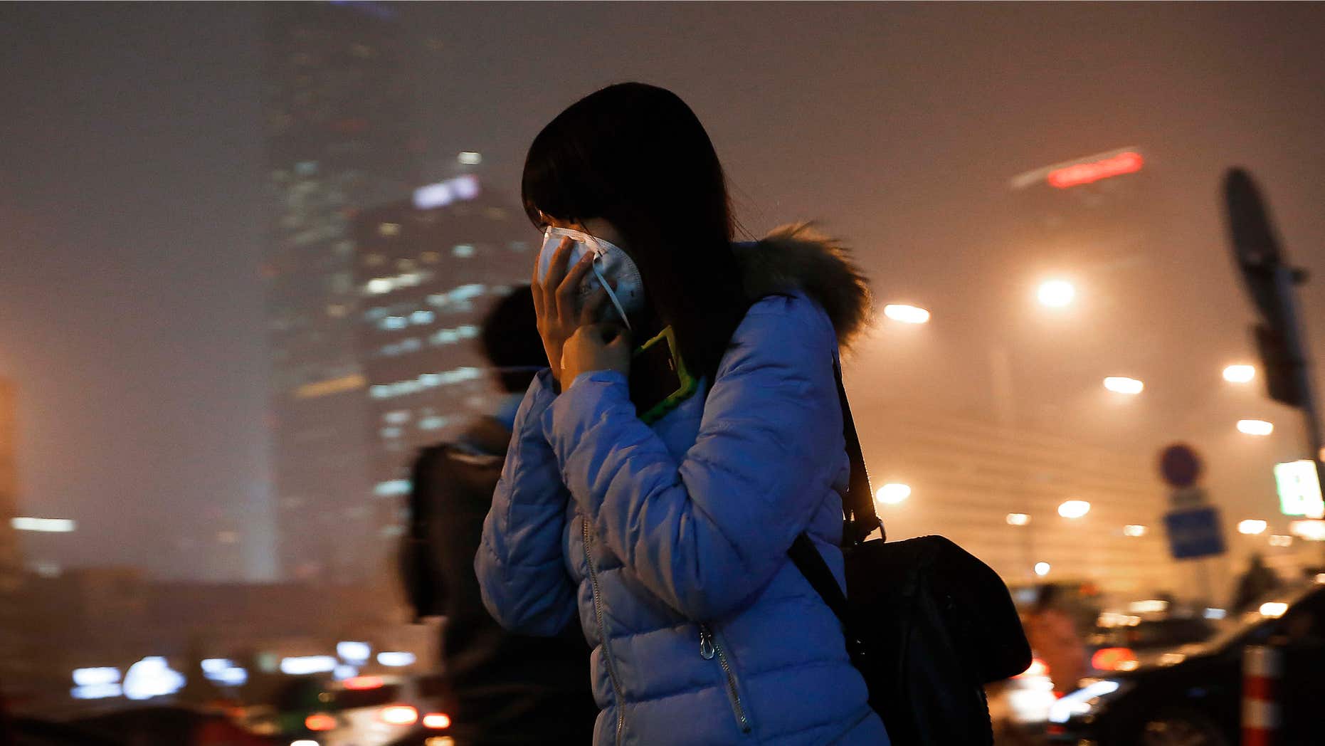 Dec. 9, 2015: A woman covers her face with a mask as she rushes to a subway station on a heavily polluted day in Beijing.