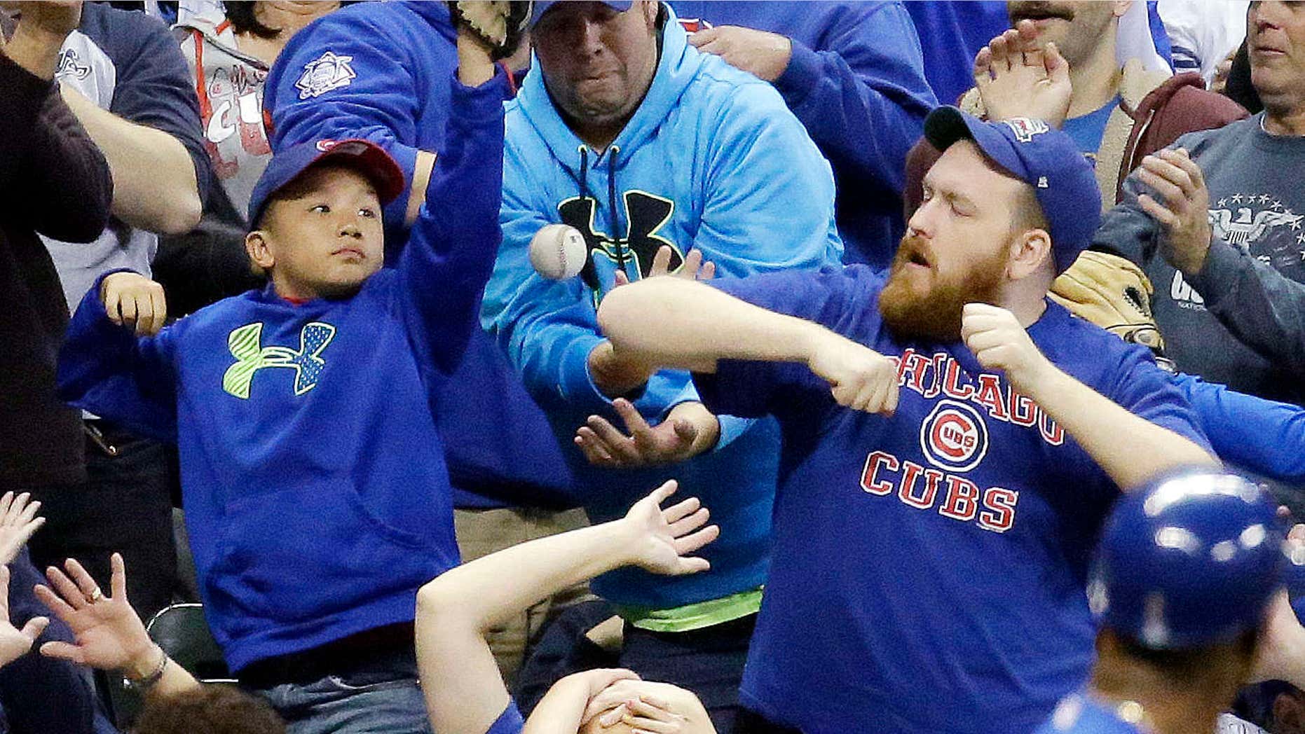 FILE - In this Oct. 2, 2015, file photo, fans go after a foul ball hit by Chicago Cubs' Dexter Fowler during the third inning of a baseball game against the Milwaukee Brewers, in Milwaukee.
