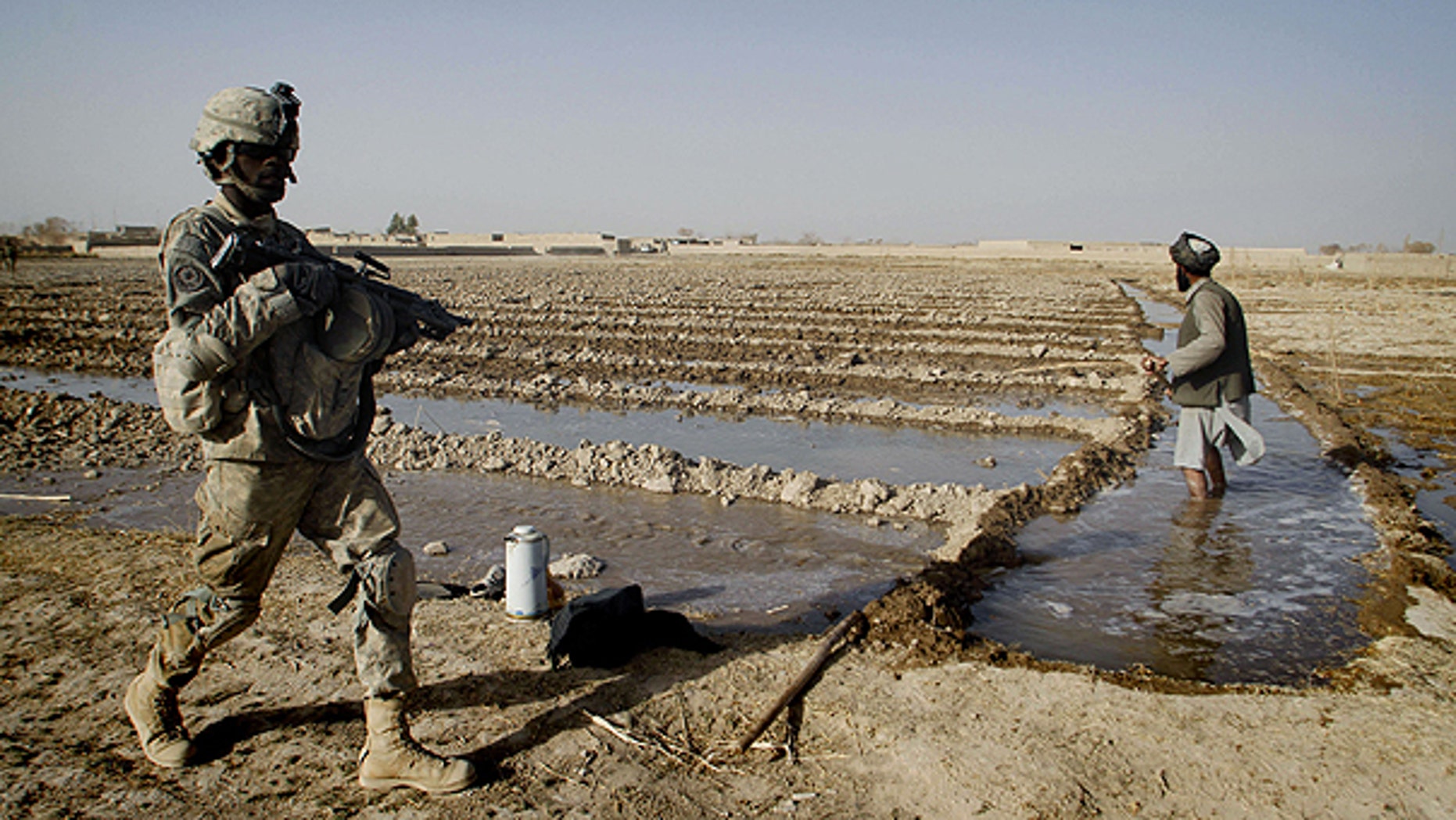 Dec. 8: A U.S. soldier passes by an Afghan farmer, who waters his farming lands during a patrol in Panjwai district of Kandahar province, south of Kabul, Afghanistan.