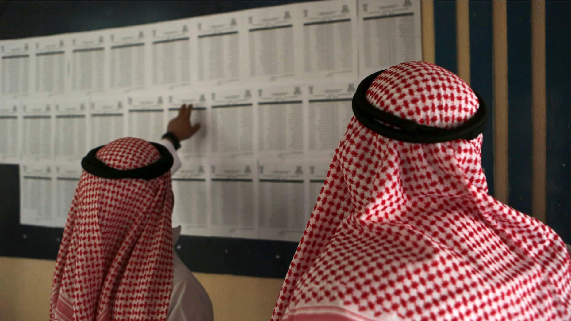 Dec. 12, 2015: Saudi citizens read the candidates' list inside a polling center during the country's municipal elections in Riyadh, Saudi Arabia.