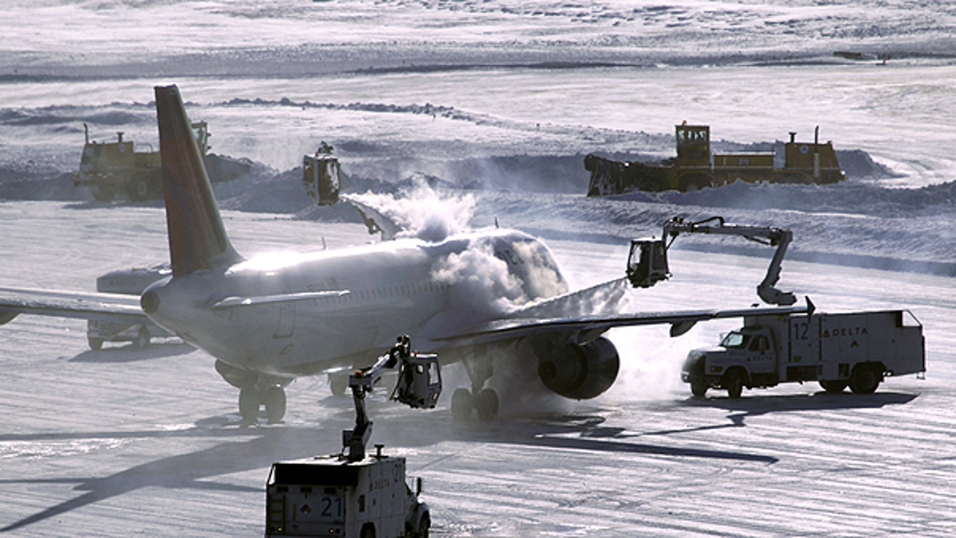 Dec. 12: A plane is de-iced before take-off while snowplows clear the runway at Minneapolis-St. Paul International Airport in Minneapolis.