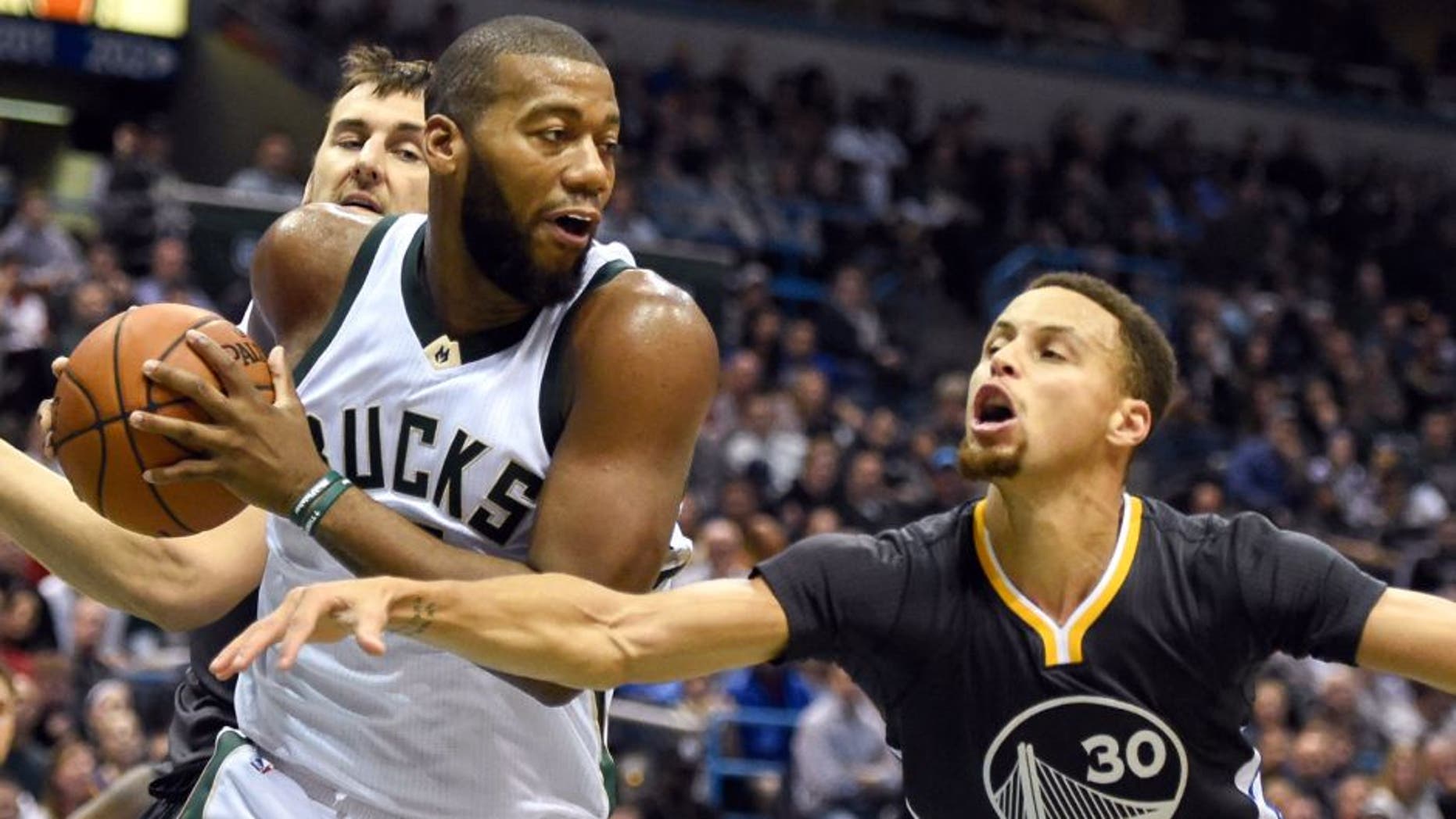 Dec 12, 2015; Milwaukee, WI, USA; Milwaukee Bucks center Greg Monroe (15) grabs a rebound against Golden State Warriors guard Stephen Curry (30) in the second quarter at BMO Harris Bradley Center. Mandatory Credit: Benny Sieu-USA TODAY Sports