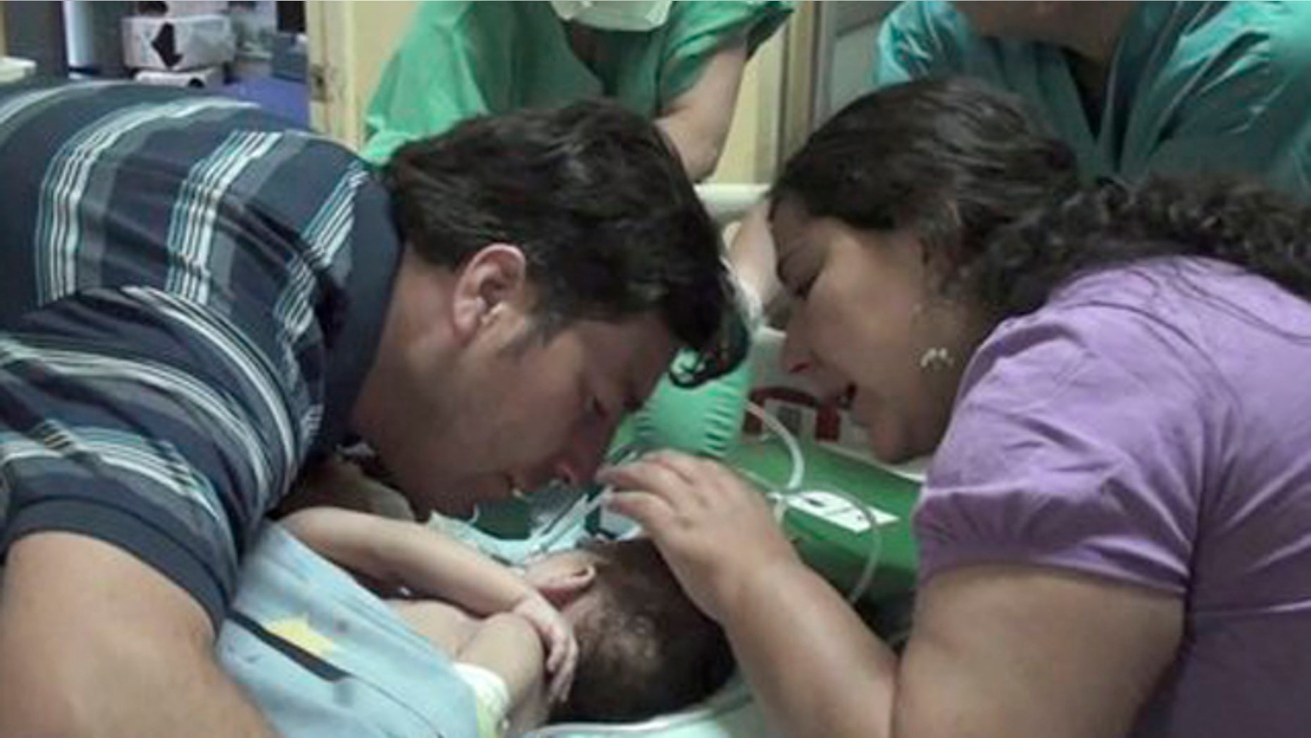 December 13, 2011: In this image taken from a video released by Luis Calvo Mackenna hospital, Jessica Navarrete, right, and Roberto Paredes, parents of conjoined twins Maria Paz and Maria Jose Paredes Navarrete kiss them before a separation surgery in Santiago, Chile.